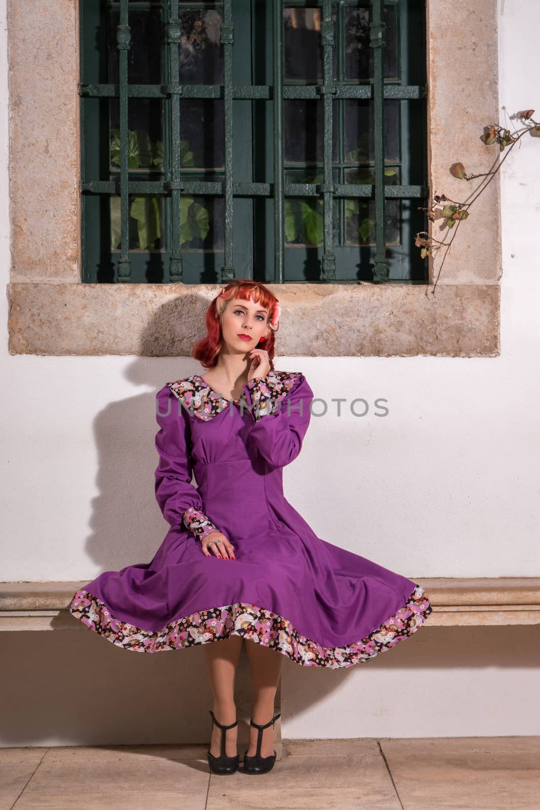 Close up view of a young redhead girl on a retro vintage dress on the urban city.