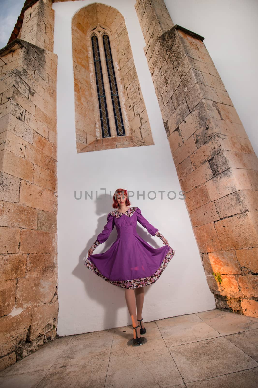 Close up view of a young redhead girl on a retro vintage dress on the urban city.