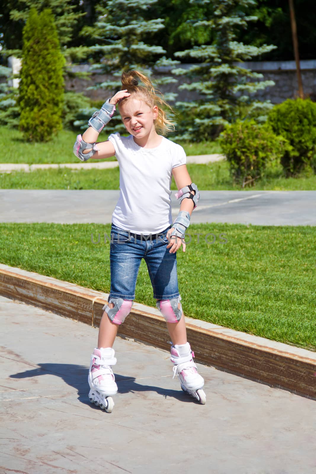 Learning girl on roller skates in summer