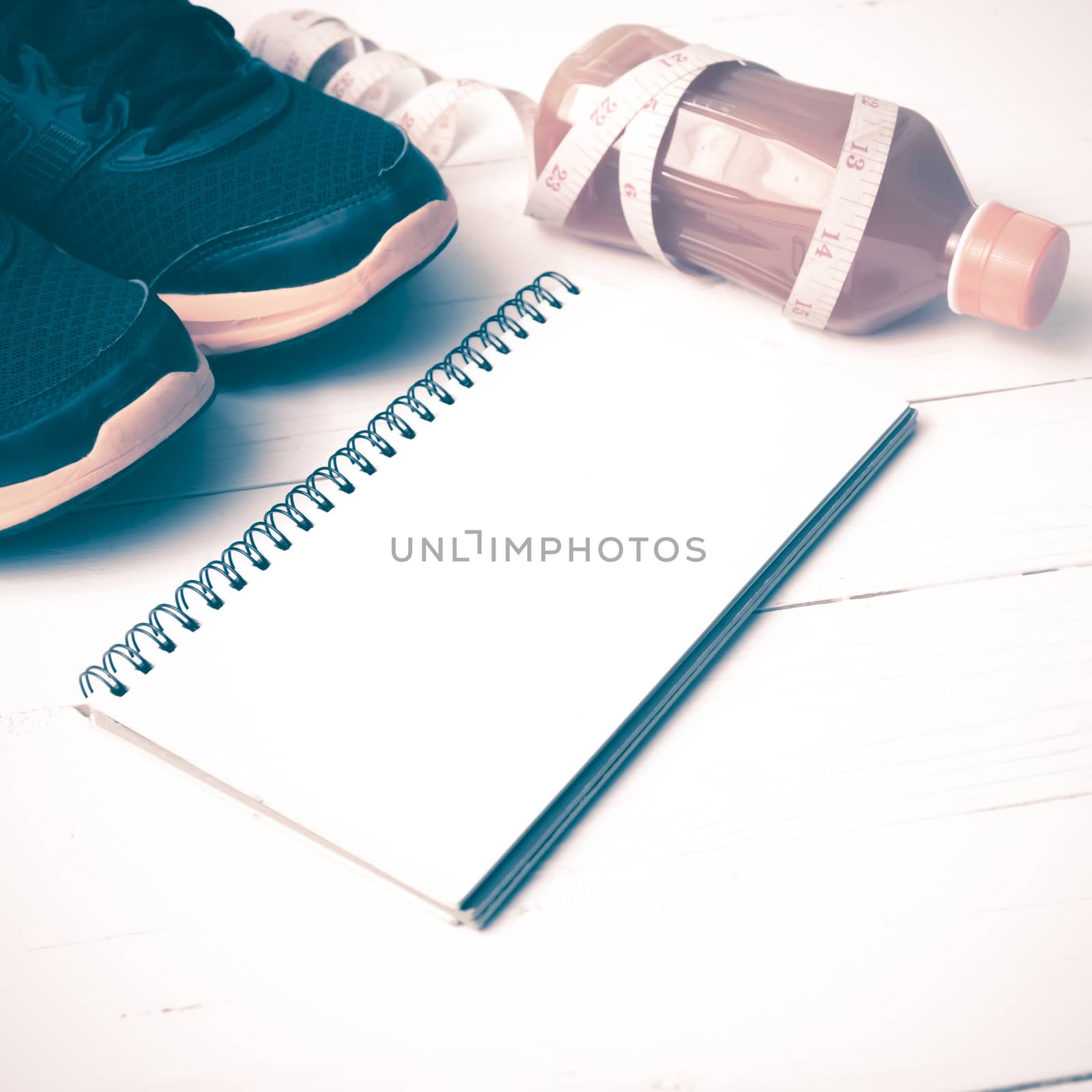 running shoes,orange juice,measuring tape and notepad on white wood background vintage tone color style