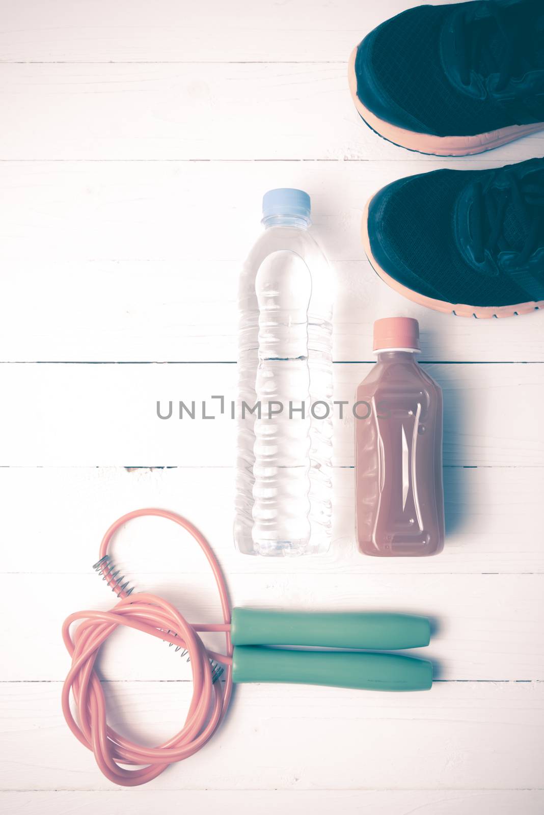 fitness equipment : running shoes,jumping rope,drinking water and orange juice on white wood background vintage tone style