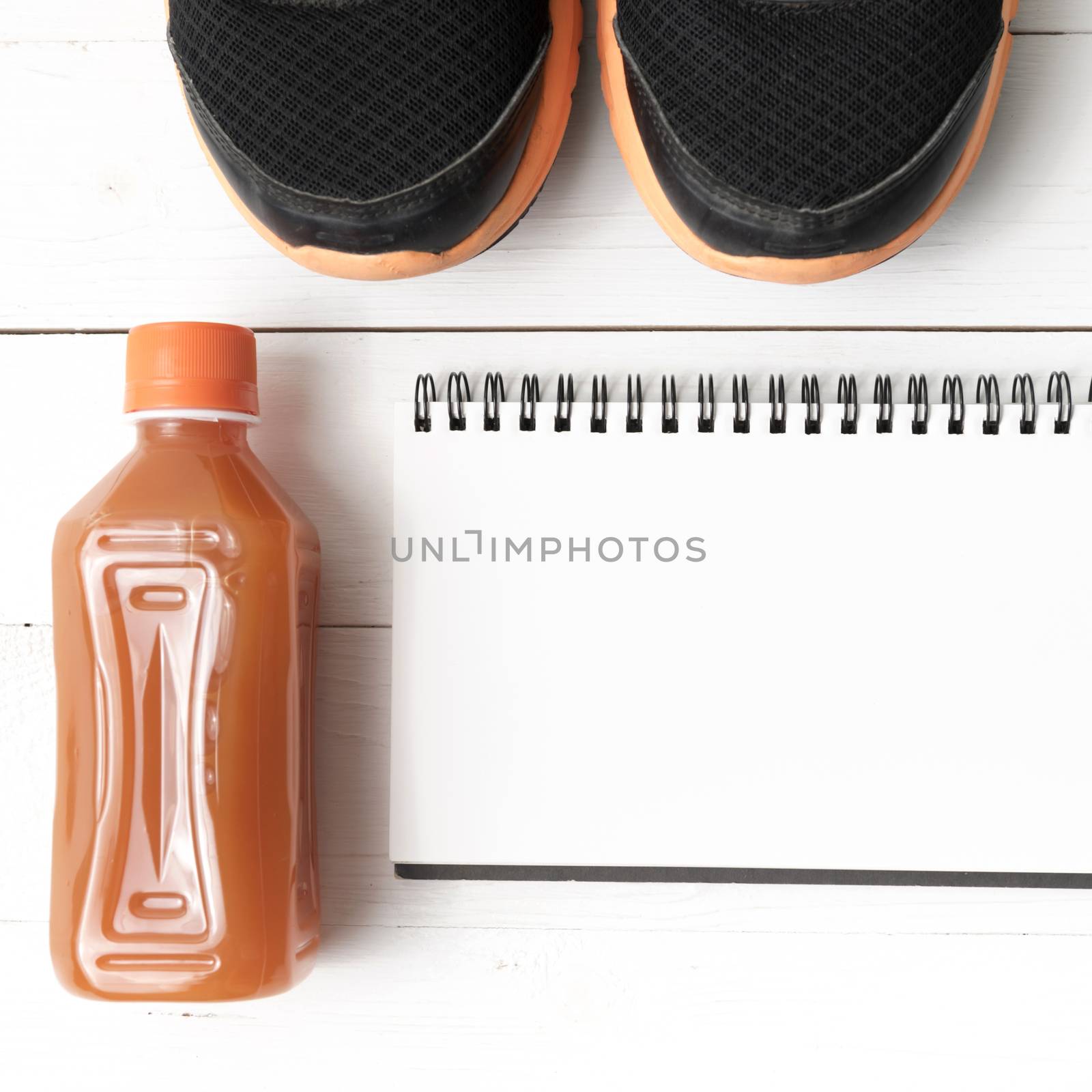 running shoes,orange juice and notepad on white wood background