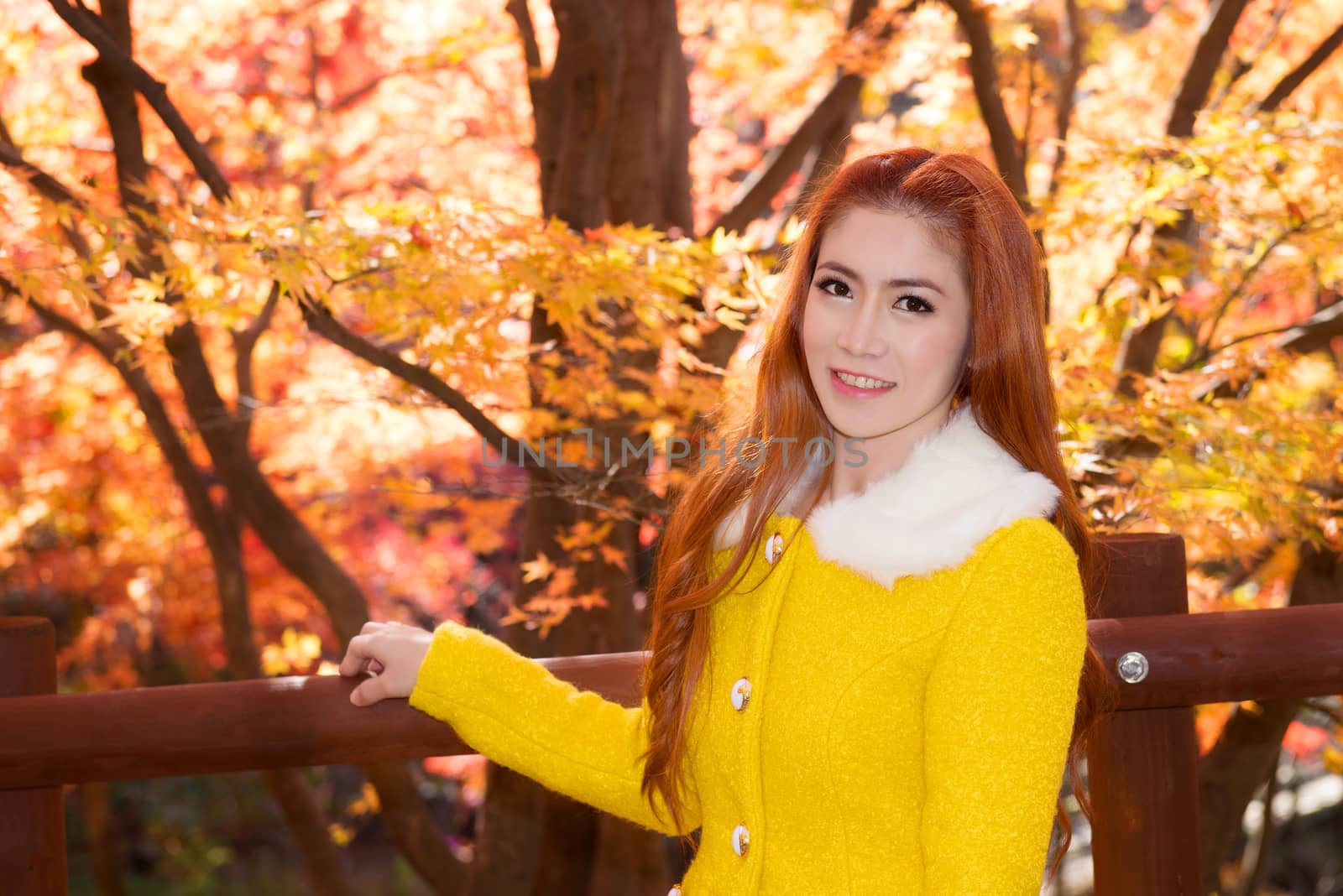 Young woman with autumn leaves in maple garden.