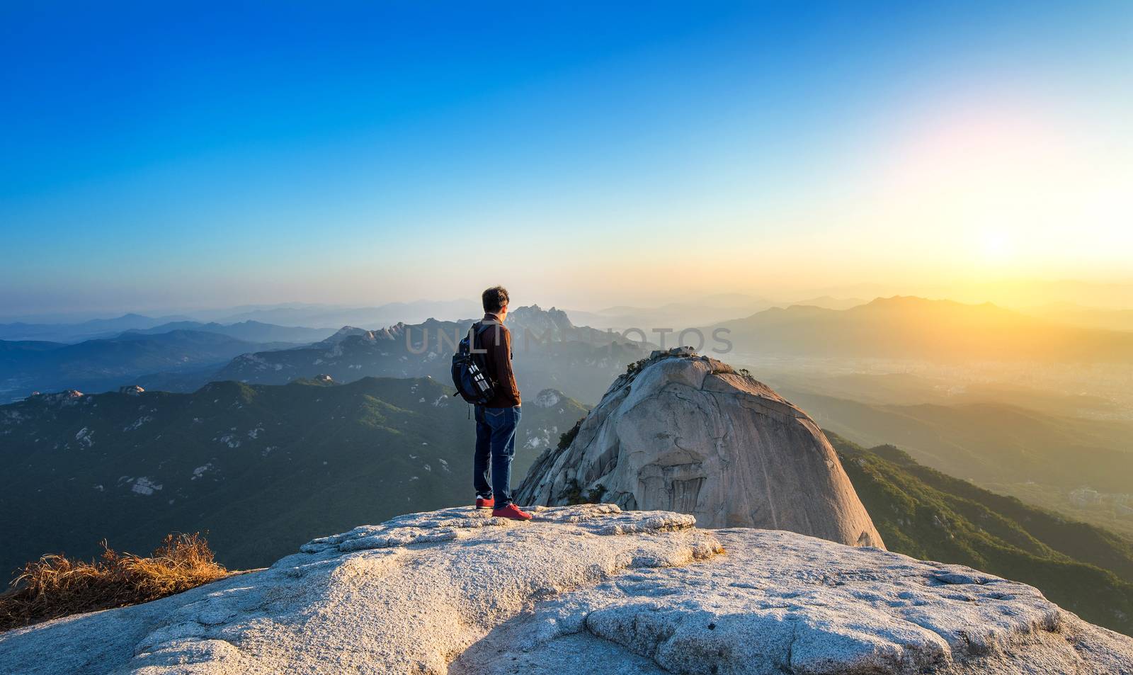 Man stands on the peak of stone in Bukhansan national park,Seoul in South Korea and watching to Sunrise. Beautiful moment the miracle of nature.