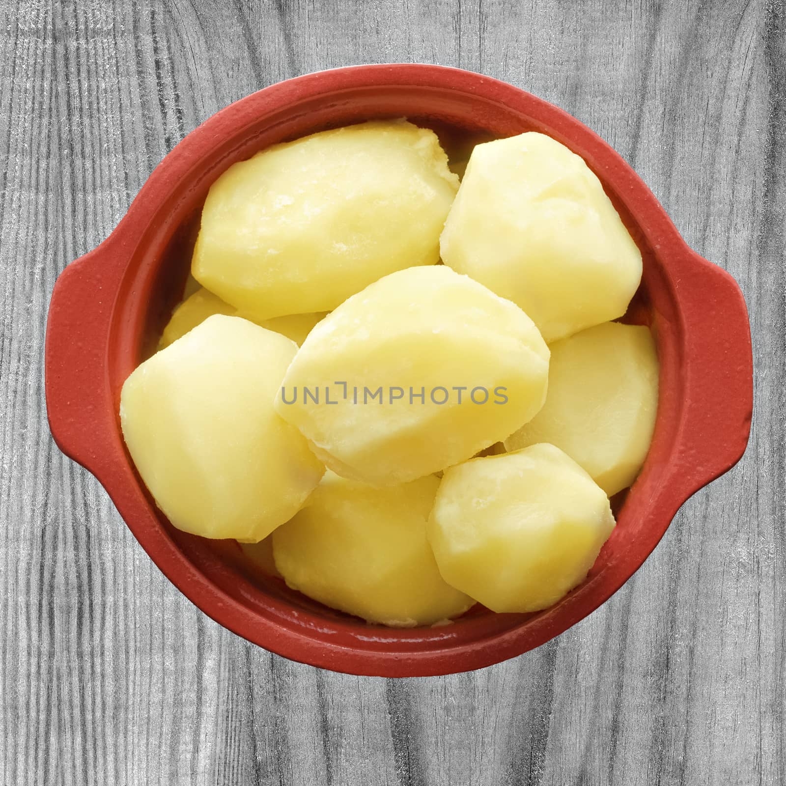 Boiled potatoes in a pot, on wooden background by Gaina