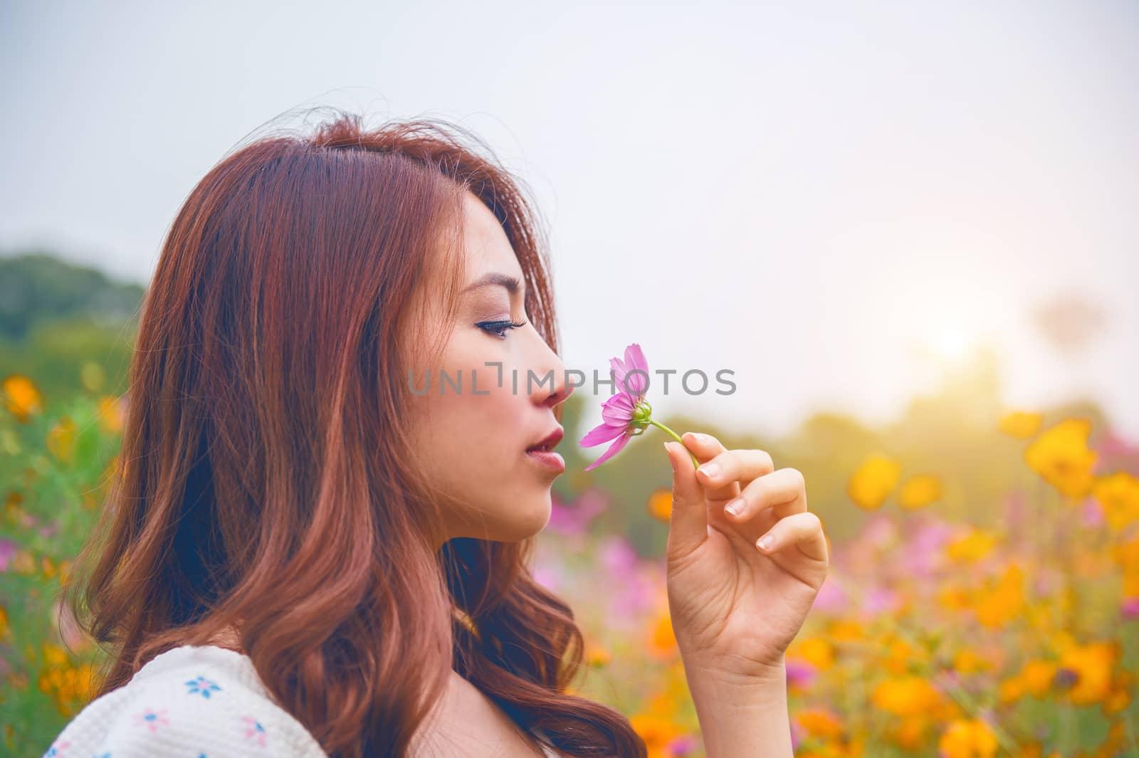 Young beautiful woman smells a flower. by gutarphotoghaphy