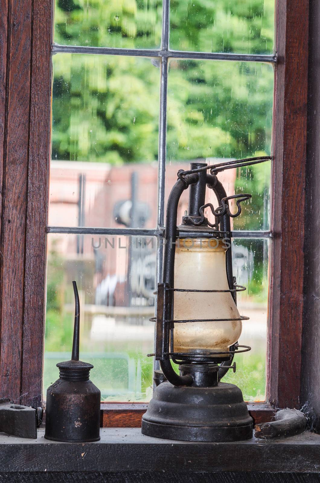 Old kerosene lamp on a window sill in the background a lattice window.