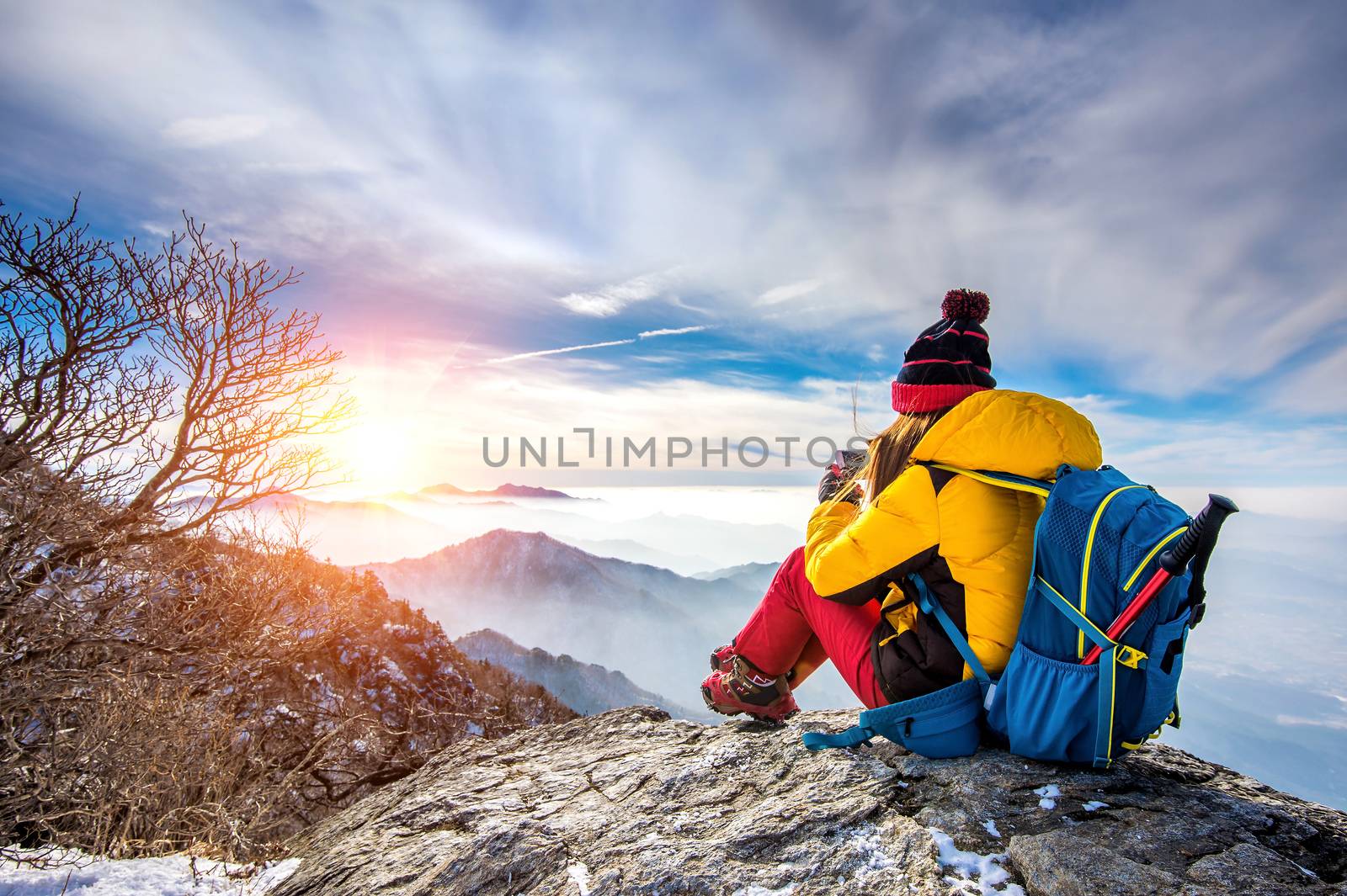 Young woman hiker taking photo with smartphone on mountains peak in winter.