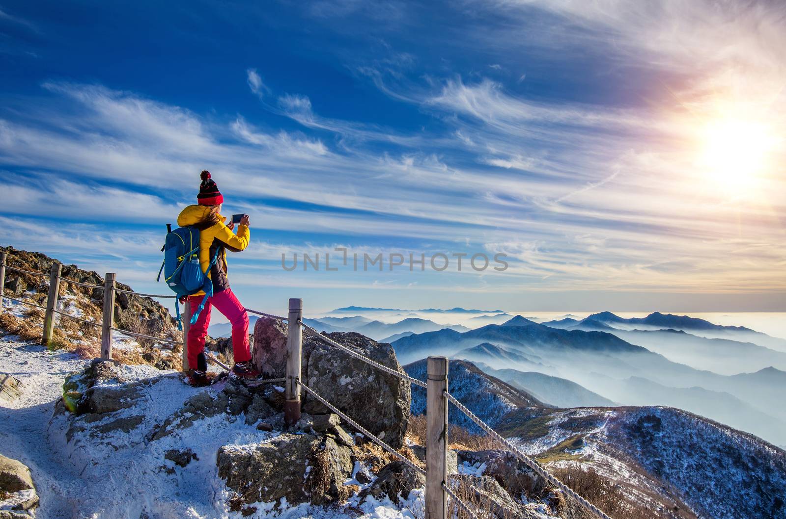 Young woman hiker taking photo with smartphone on mountains peak by gutarphotoghaphy