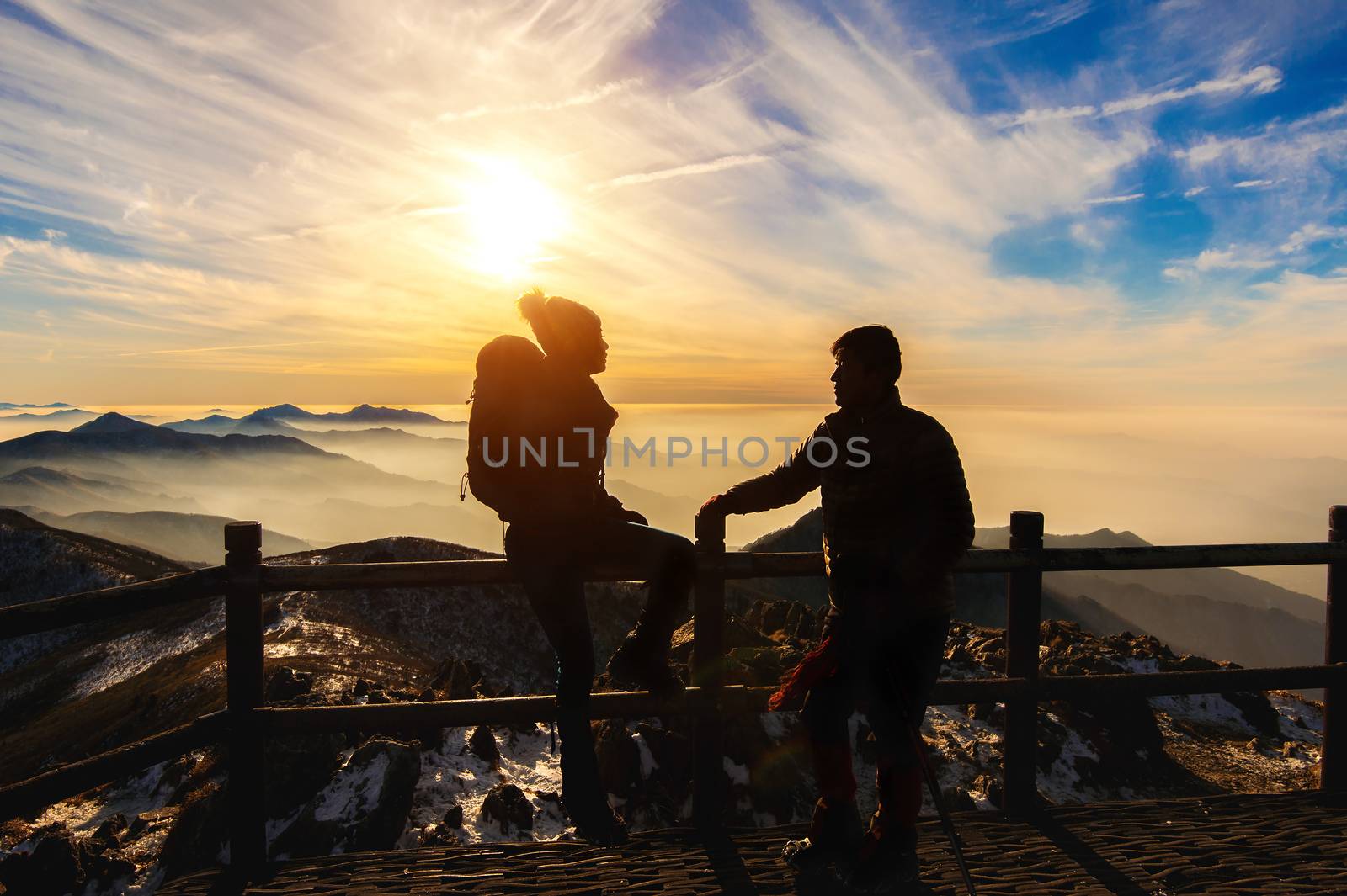 Silhouette of young woman and man with backpacks and sticks on m by gutarphotoghaphy
