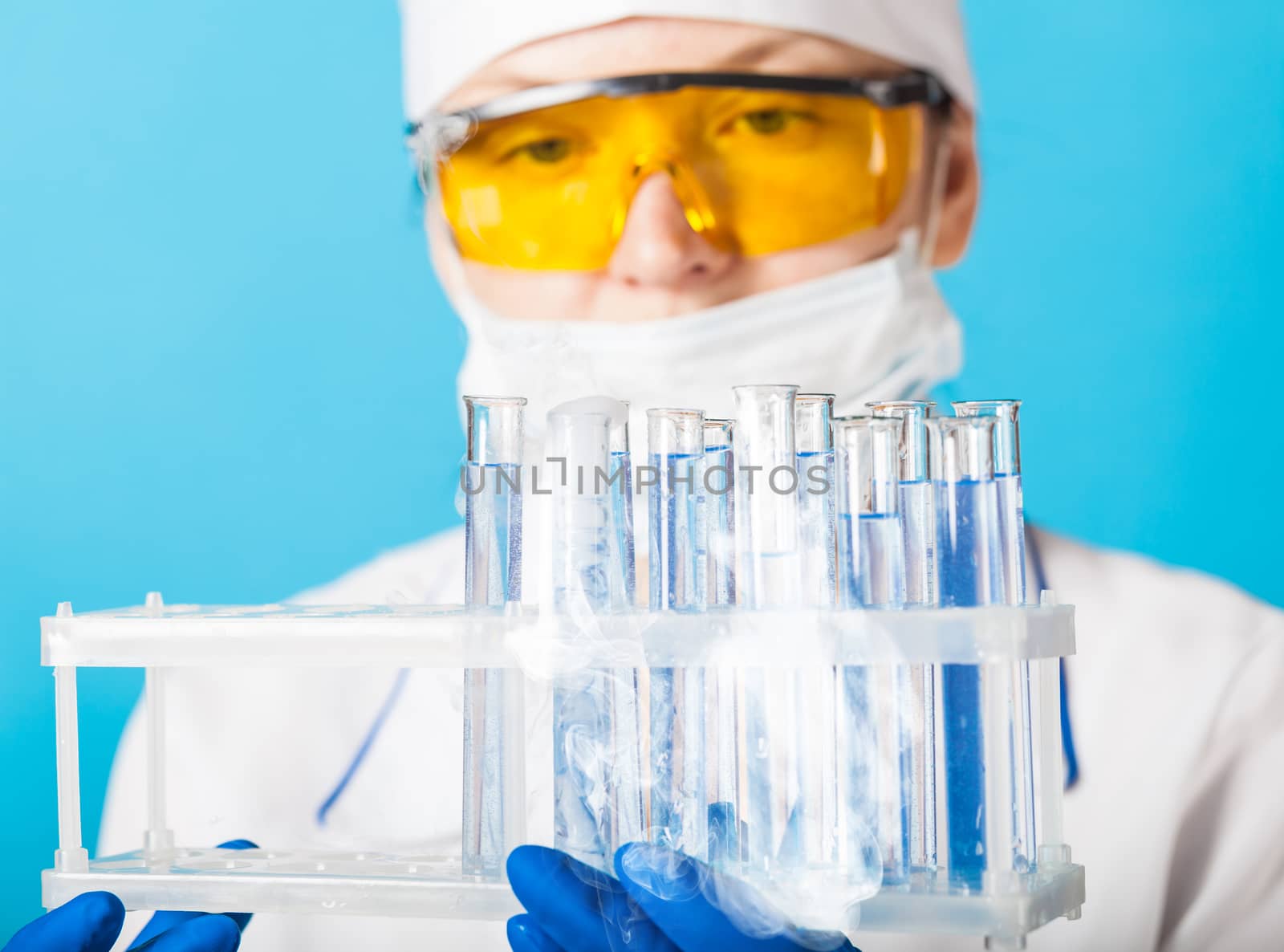 Woman chemist examines test tube on a blue background