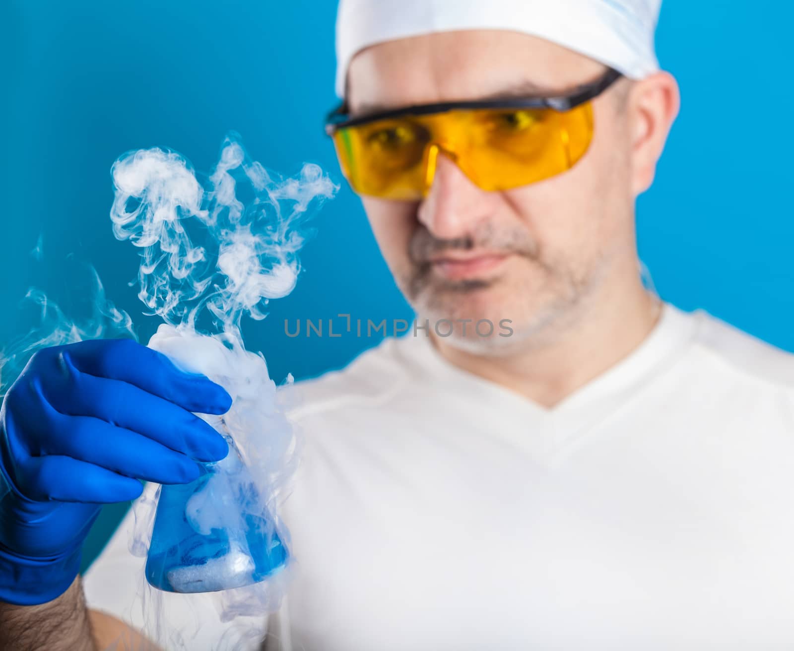 man chemist examines test tube on a blue background