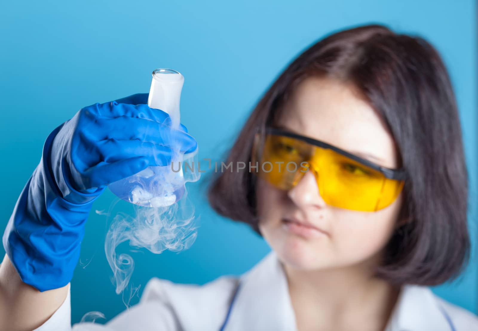 Woman chemist examines test tube on a blue background