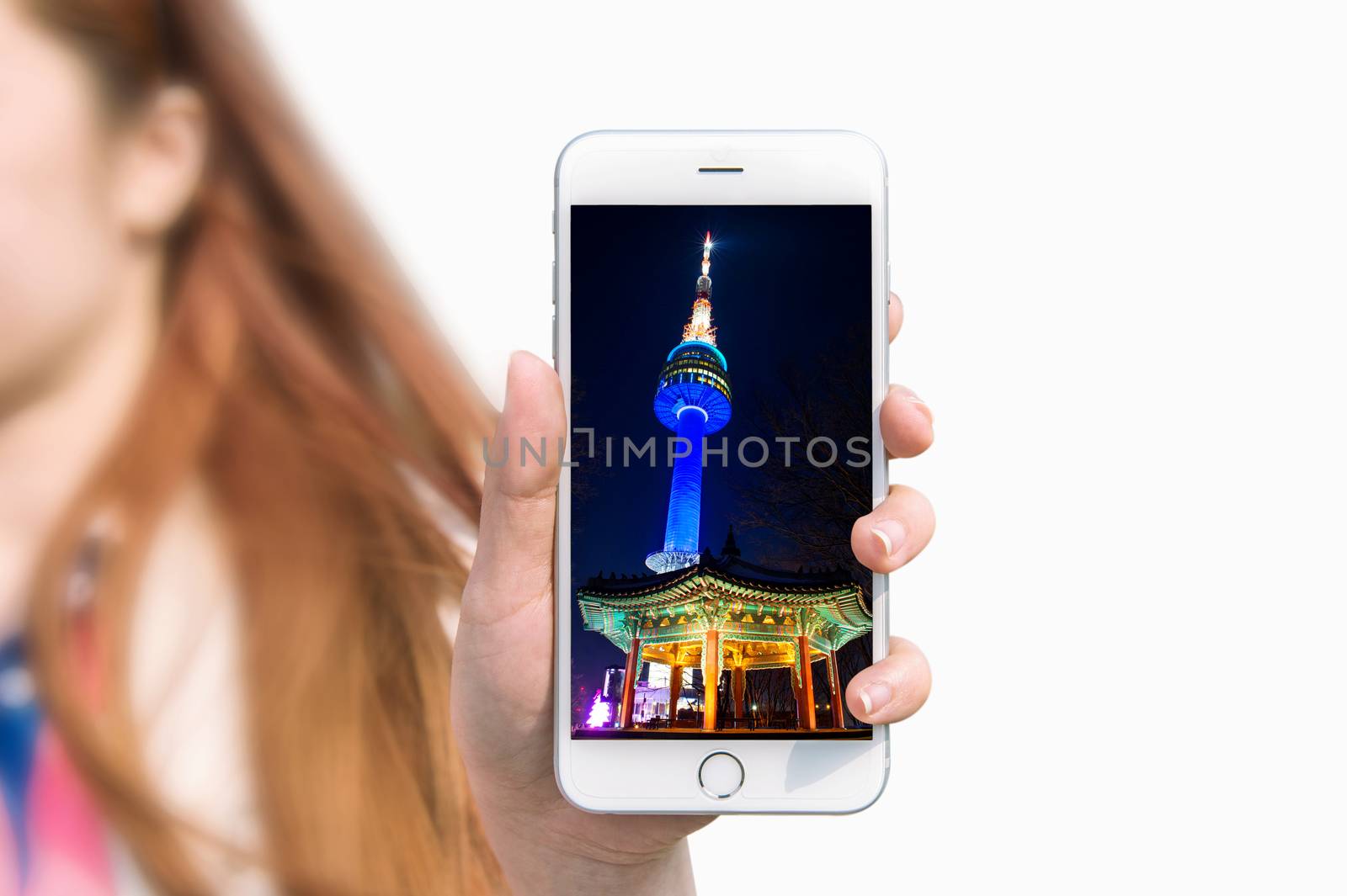 Hand holding smart phone with photo of Seoul tower isolated on white background.