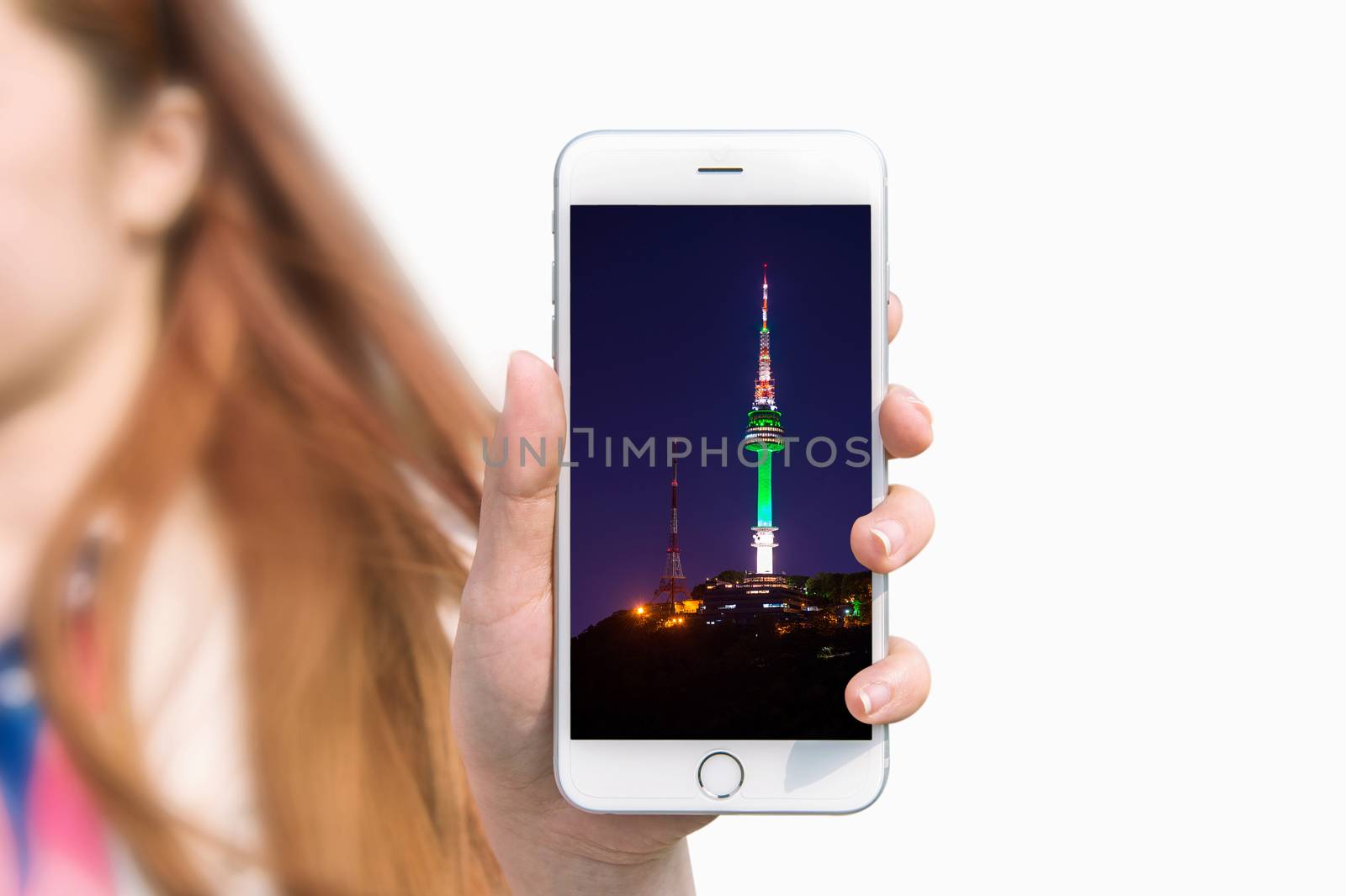 Hand holding smart phone with photo of Seoul tower isolated on white background.