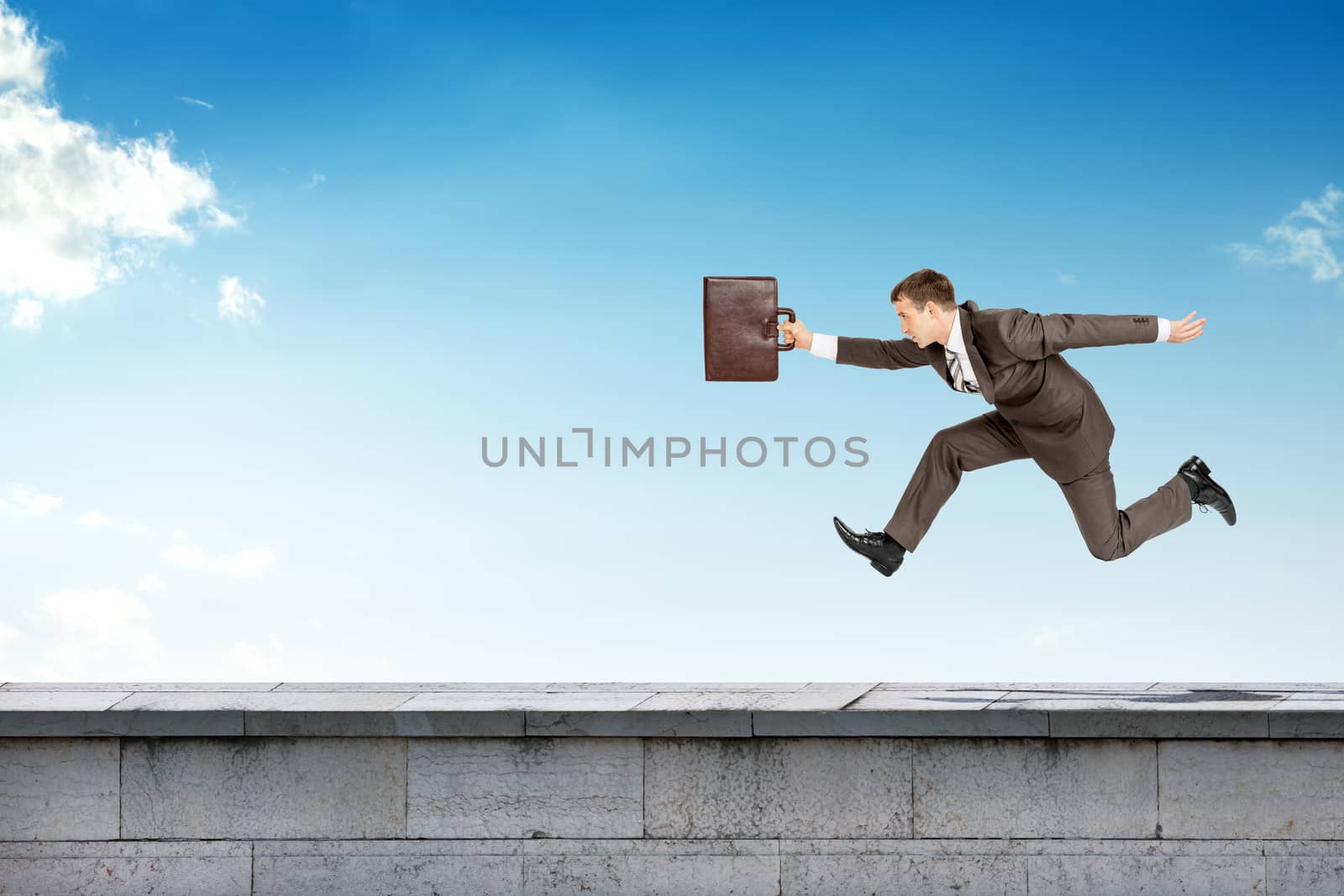 Businessman running on building roof by cherezoff