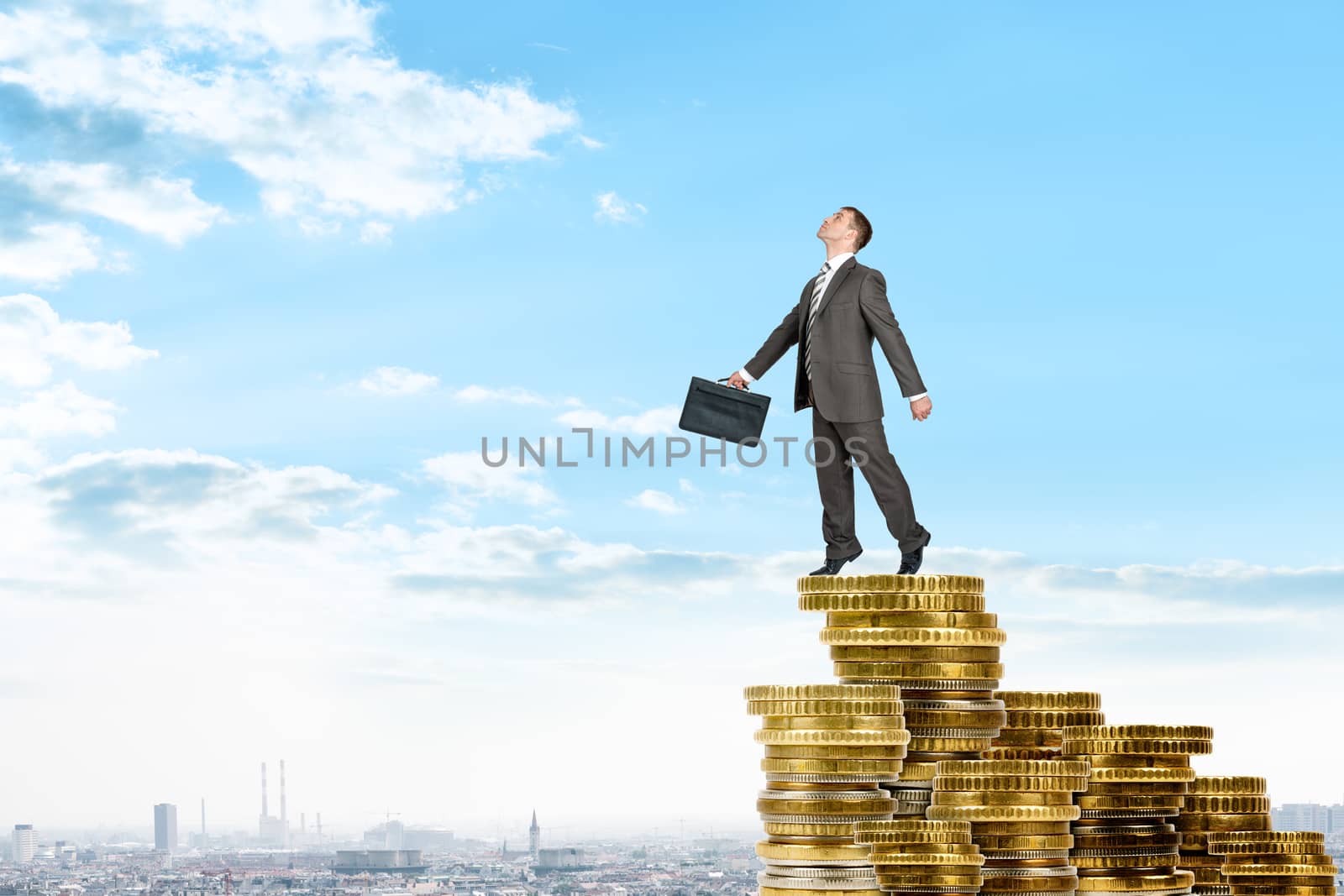 Businessman on pile of coins, business concept