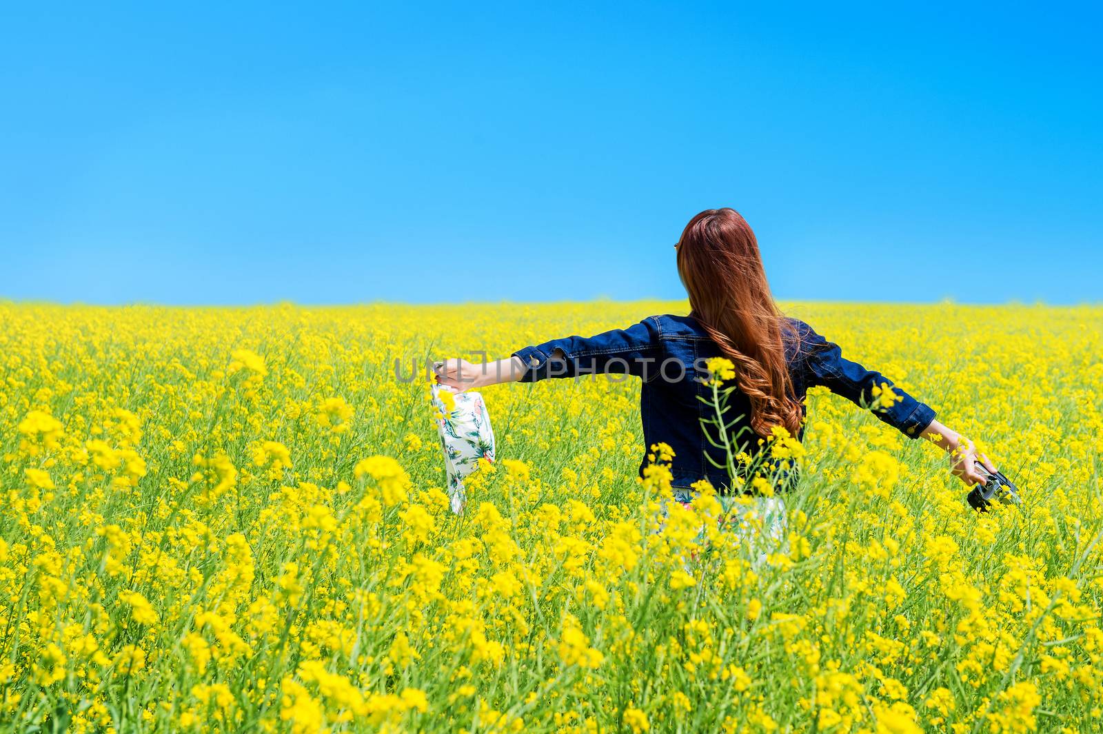 Young woman standing in yellow rapeseed field. by gutarphotoghaphy