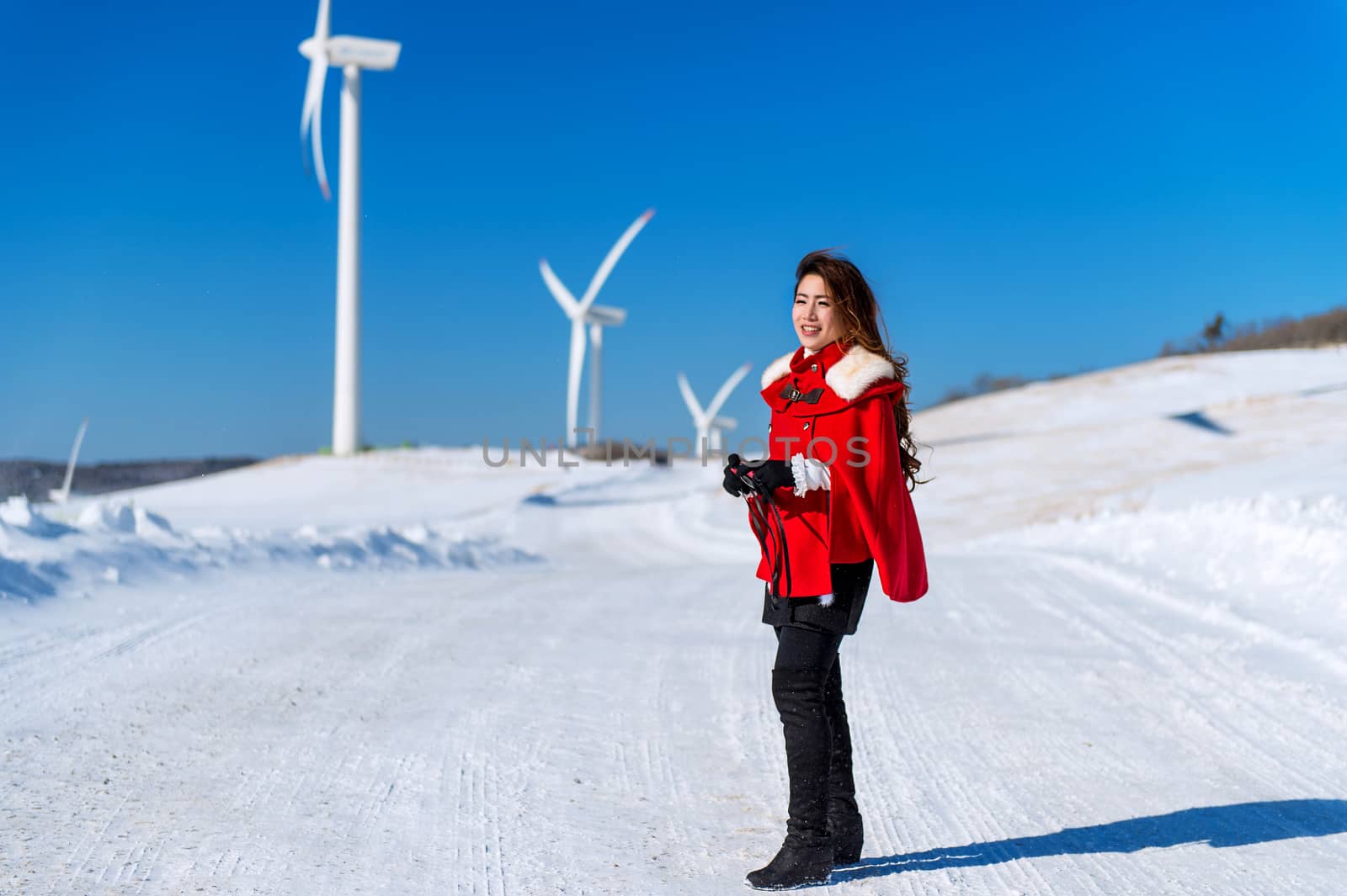 Young woman is a happiness with camera in winter of sky and winter road with snow and red dress.