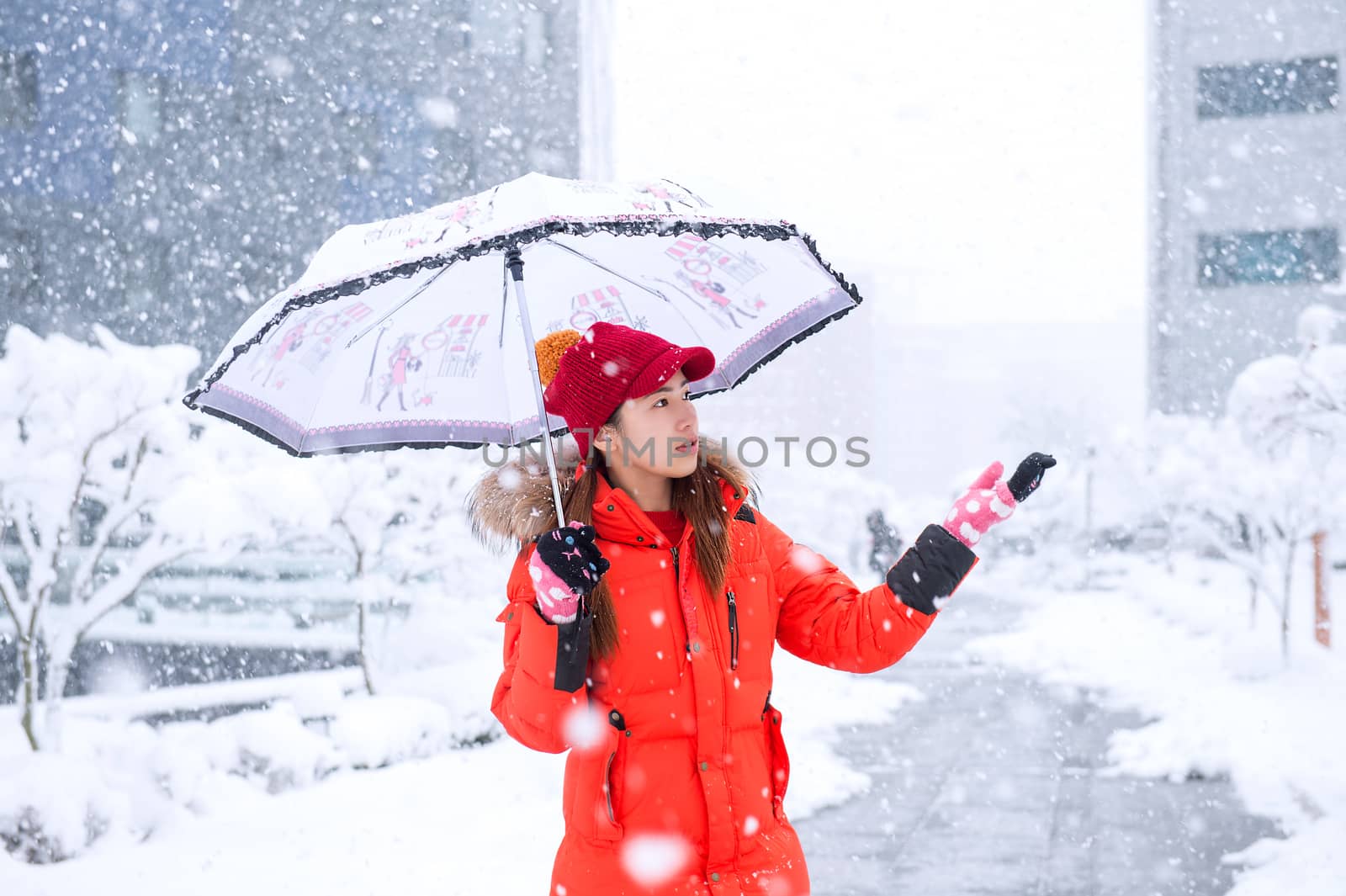 Snow falling on beautiful girl with umbrella in winter.