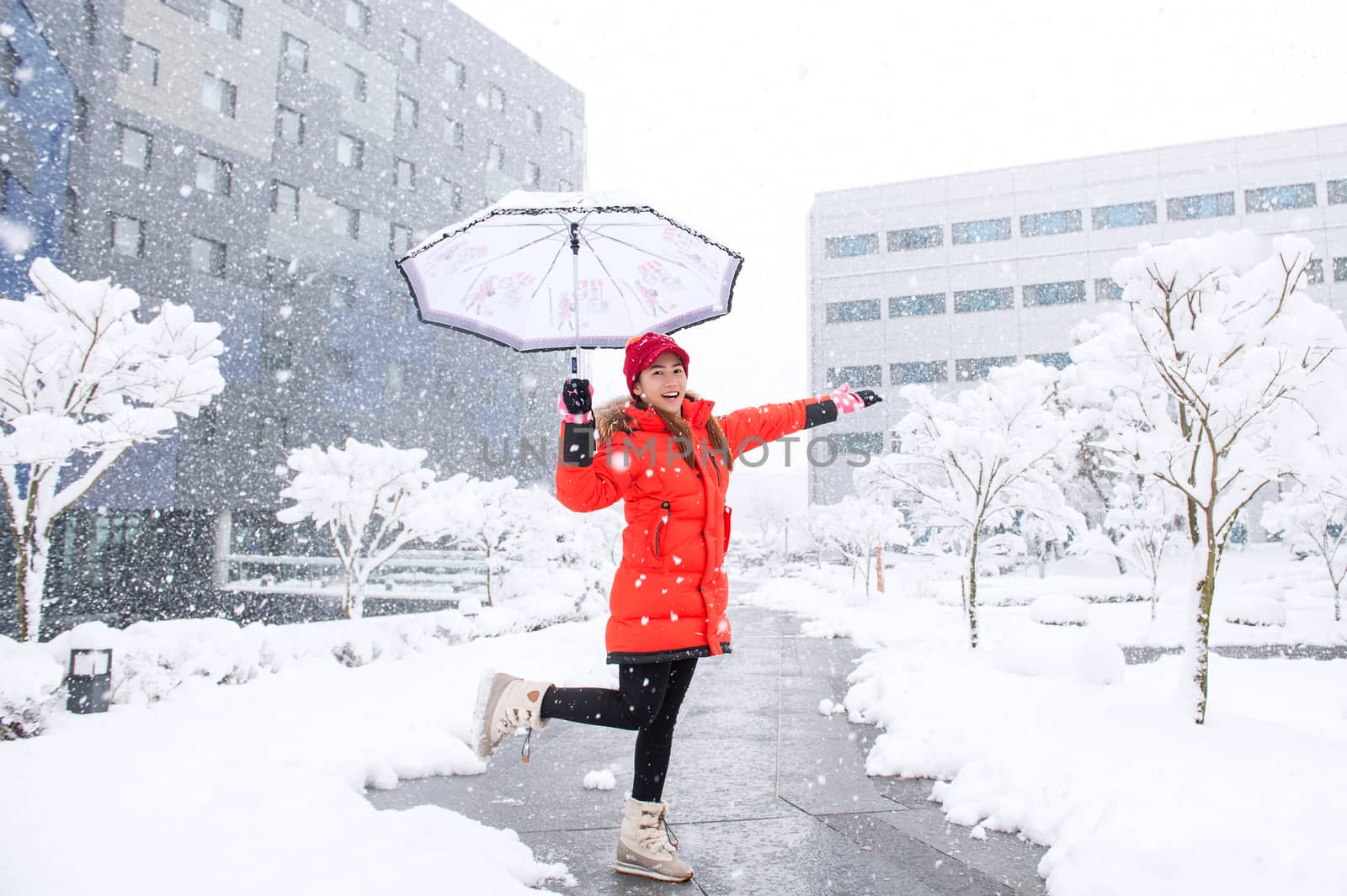 Snow falling on beautiful girl with umbrella in winter.