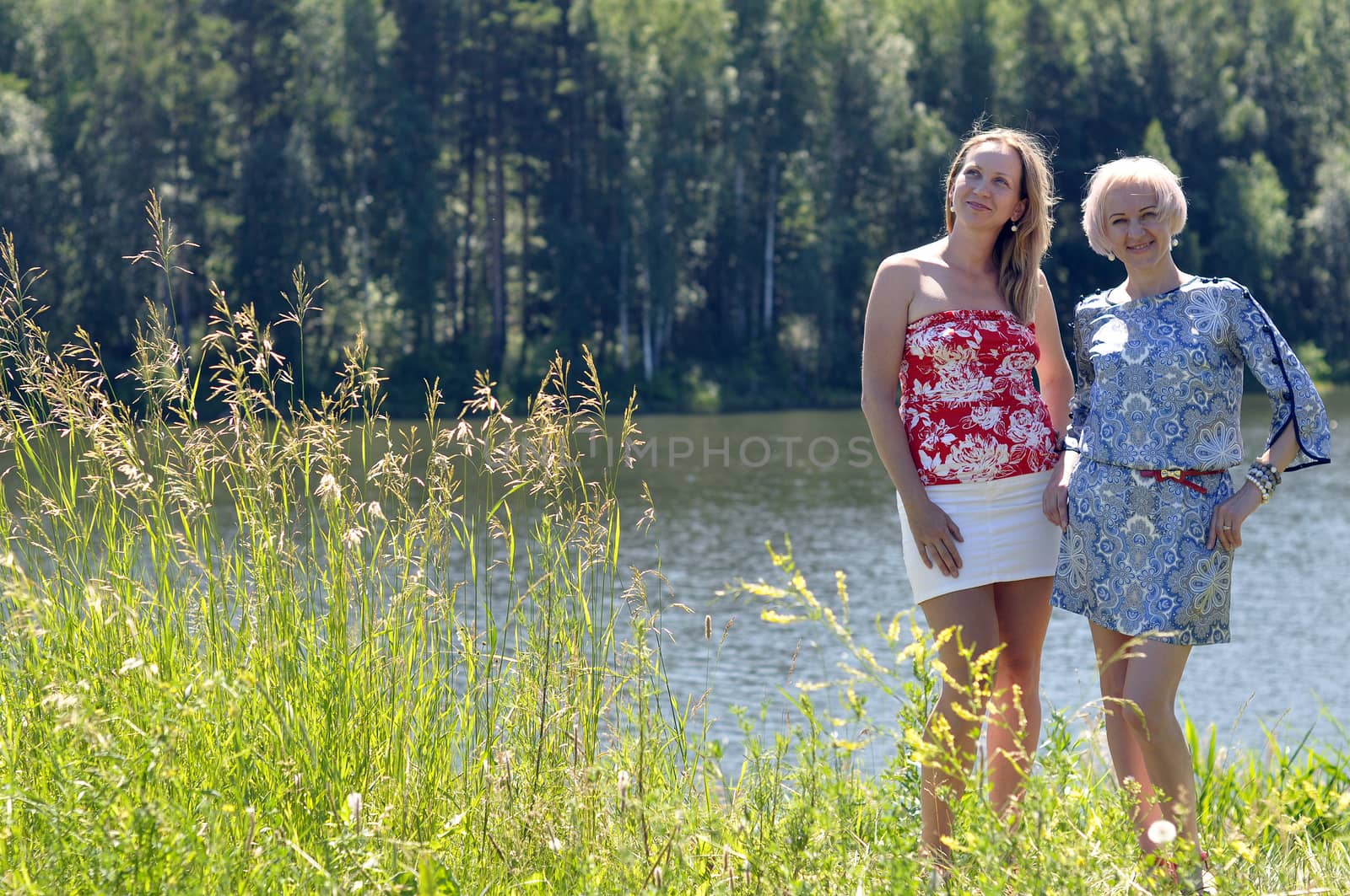 Two beautiful women have a rest in the hot summer at the river
