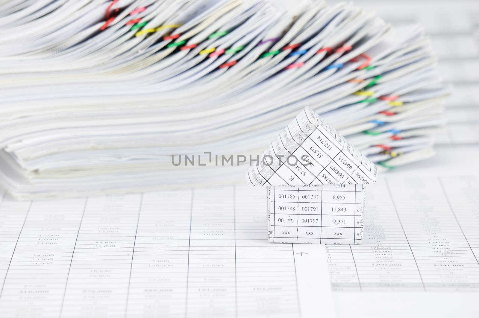 House on finance account have blur overload of paperwork with colorful paperclip as background.