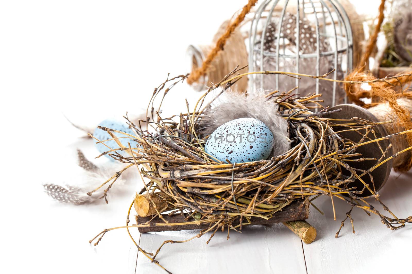 Easter eggs nest with birdcage, on white wooden background