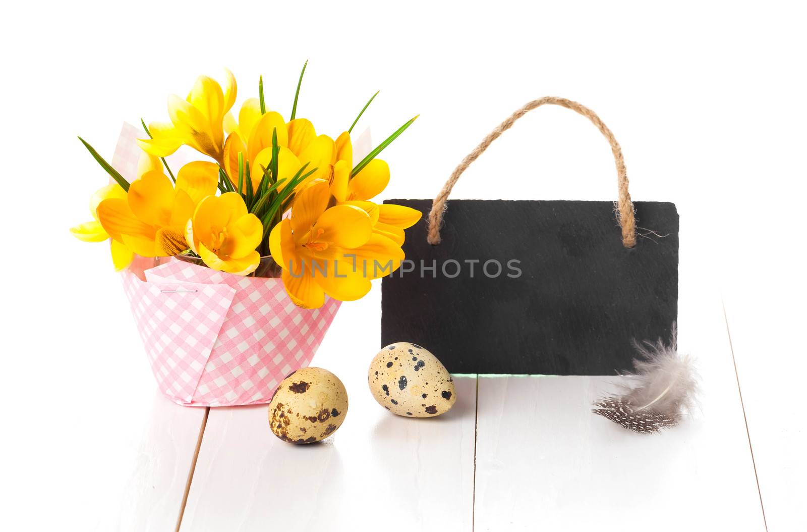 easter decoration with quail eggs, yellow Spring Crocus, and blackboard, with space for text, on wooden white background.