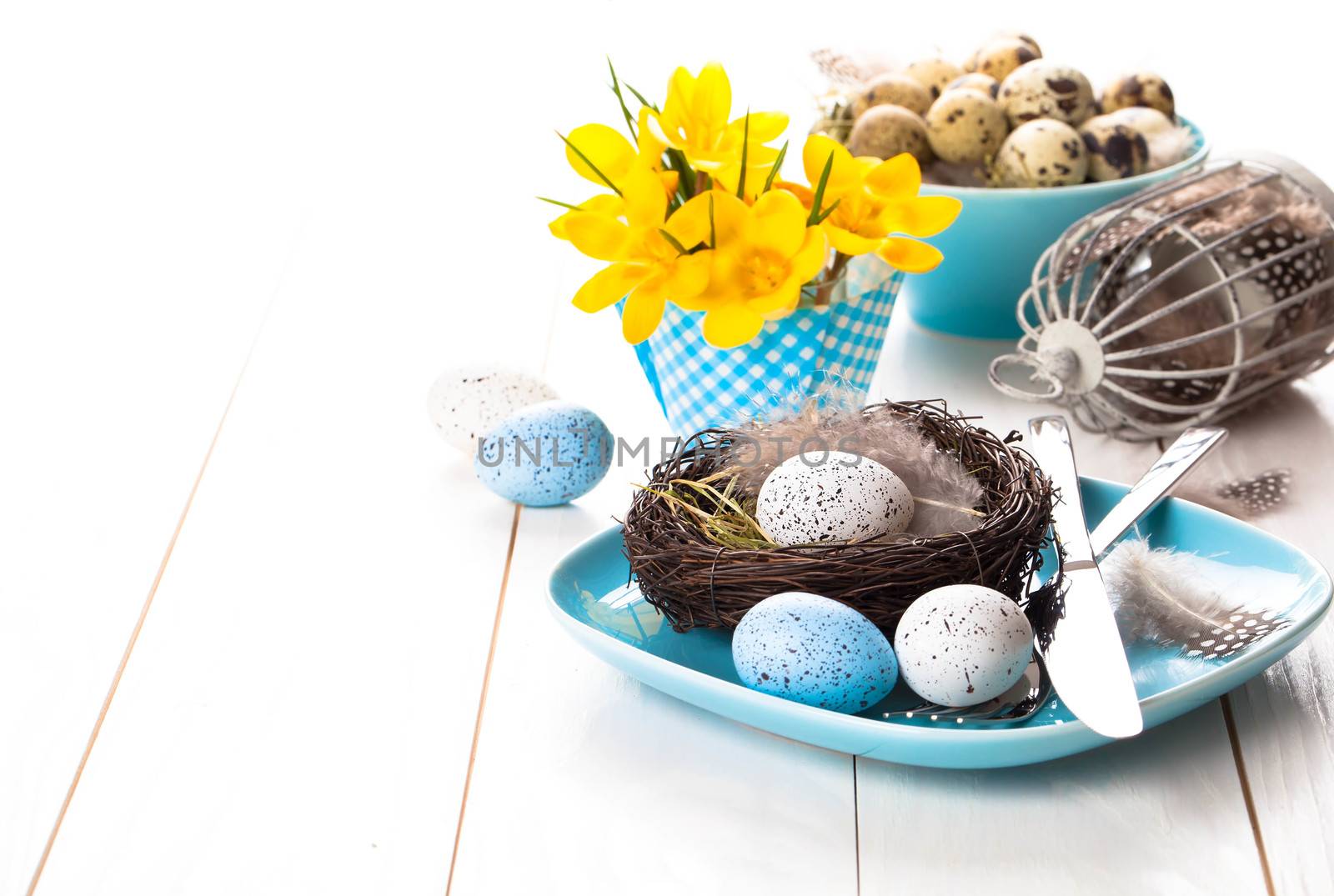 table decoration with easter eggs nest on plate, on white wooden by motorolka