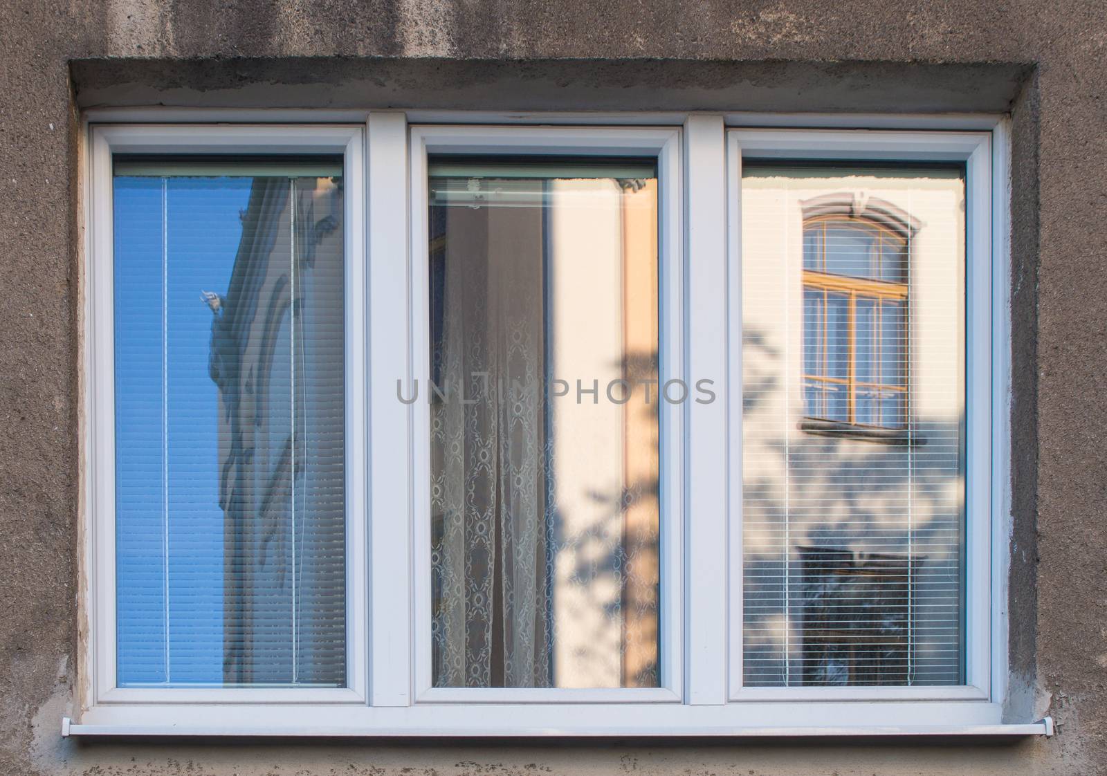 New white frames of the window, reflecting old yellow building and blue sky.