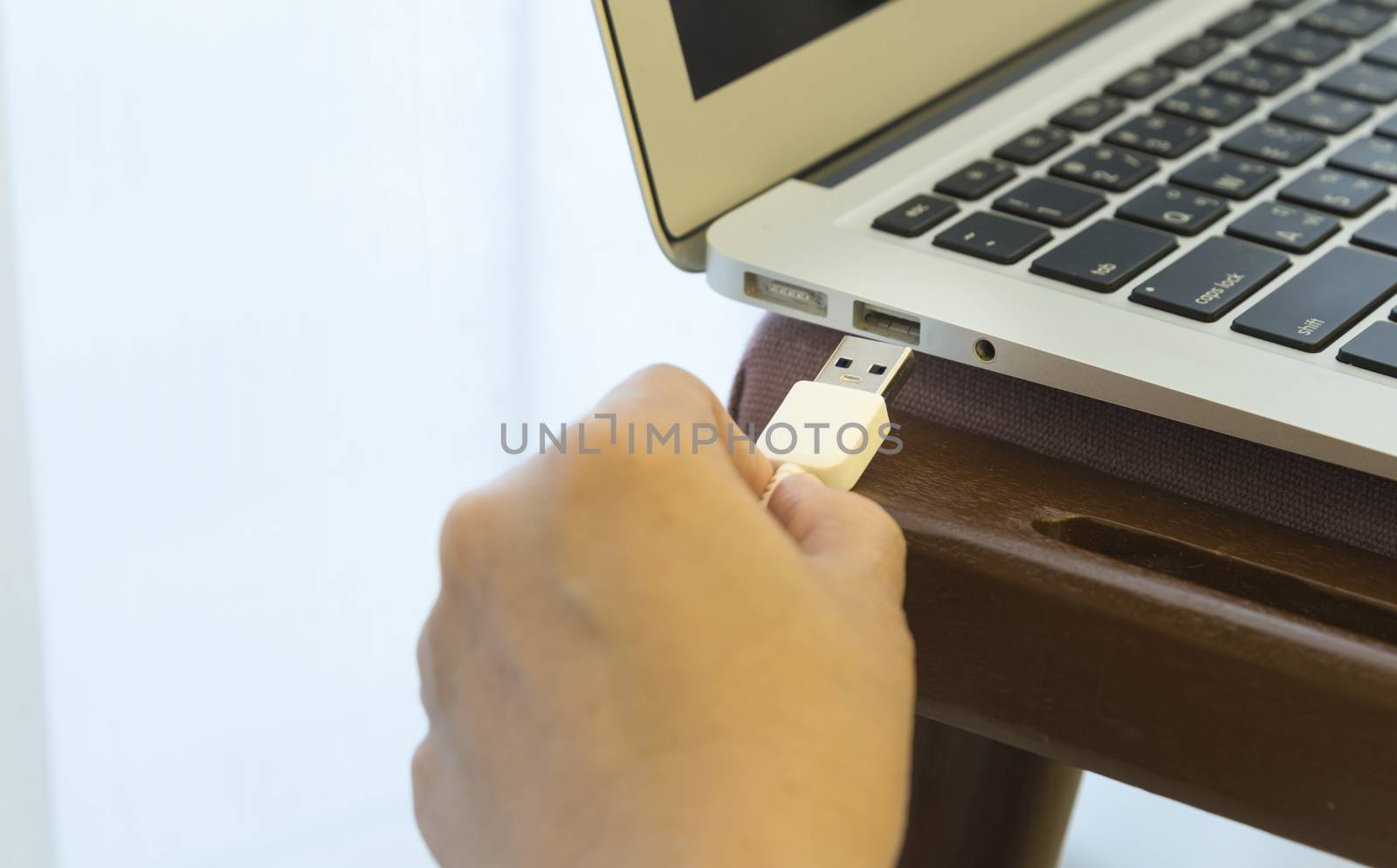Women plug external devices to the laptop with her.