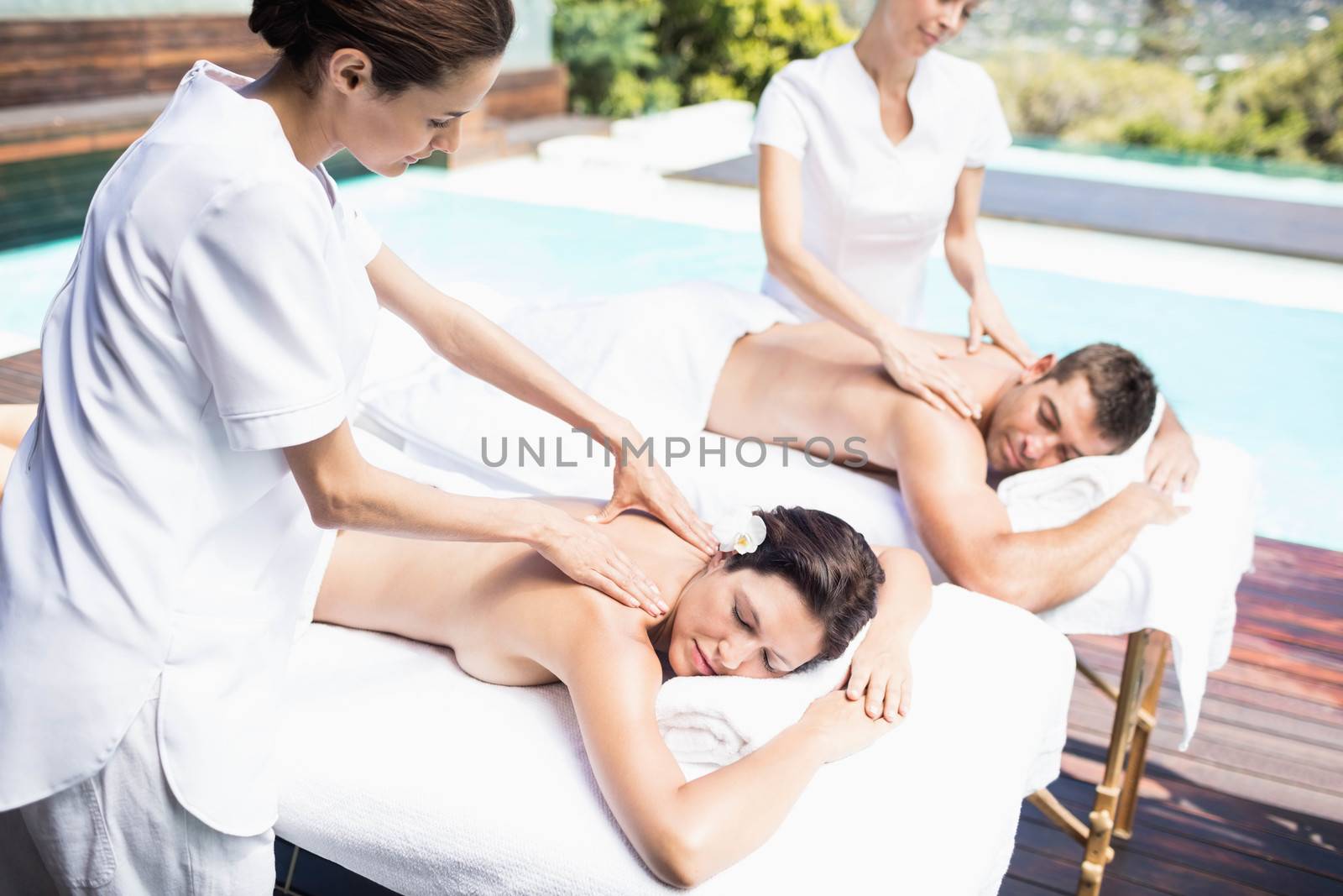 Relaxed young couple receiving a back massage from masseur in a spa