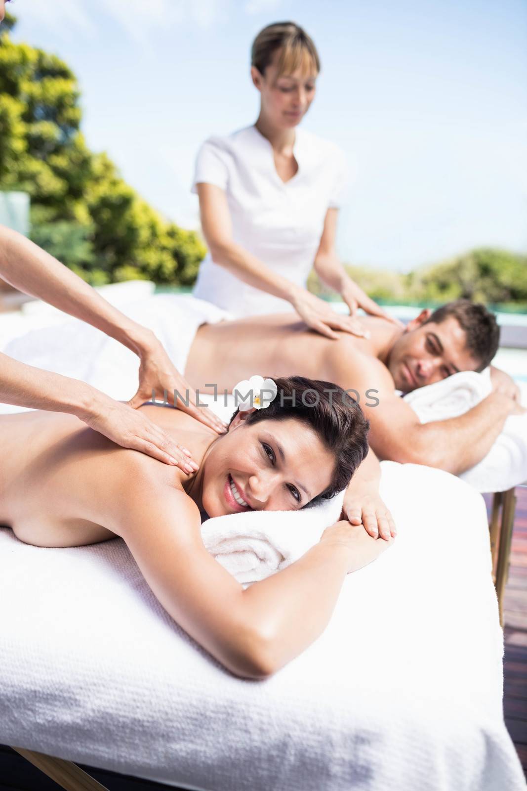 Relaxed young couple receiving a back massage from masseur in a spa 