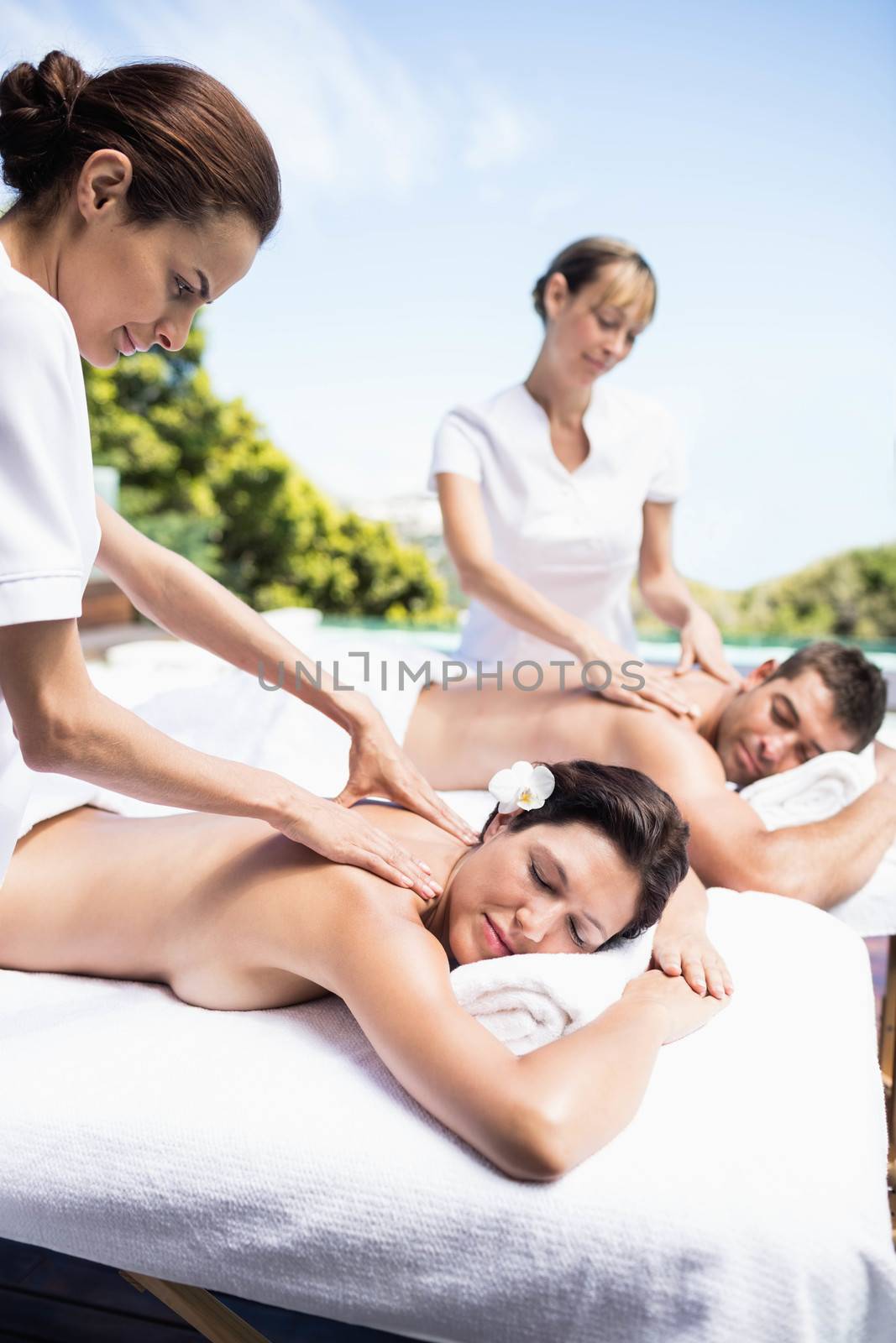Relaxed young couple receiving a back massage from masseur in a spa 