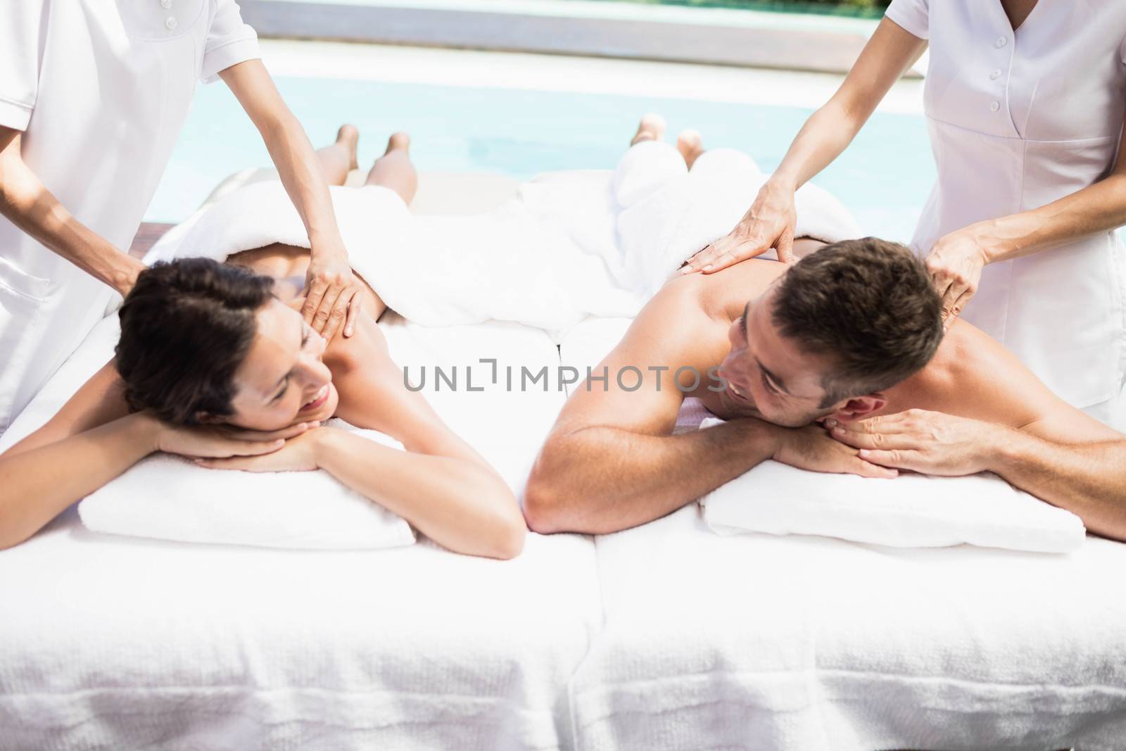 Relaxed young couple receiving a back massage from masseur in a spa