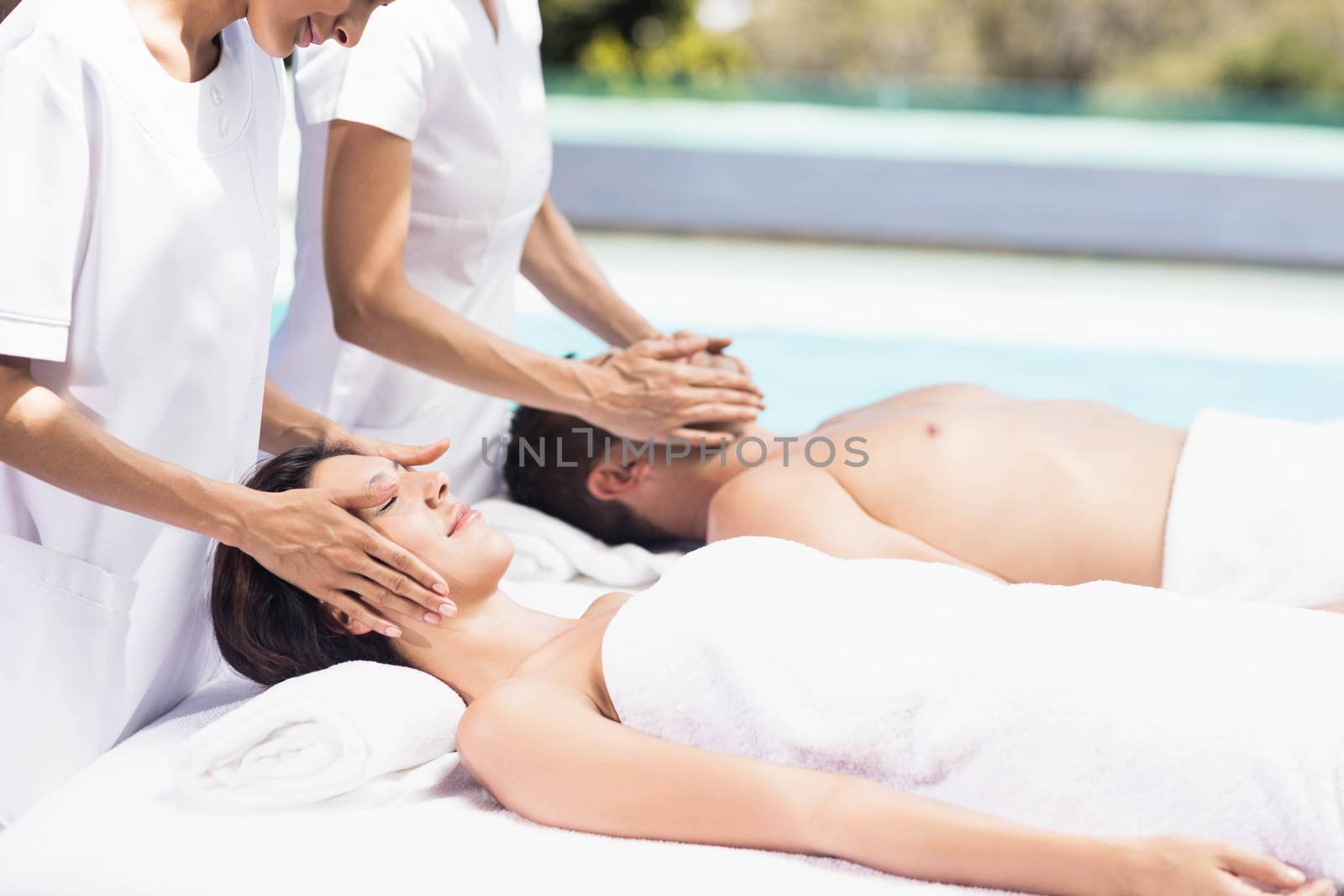 Couple receiving a face massage from masseur in a spa