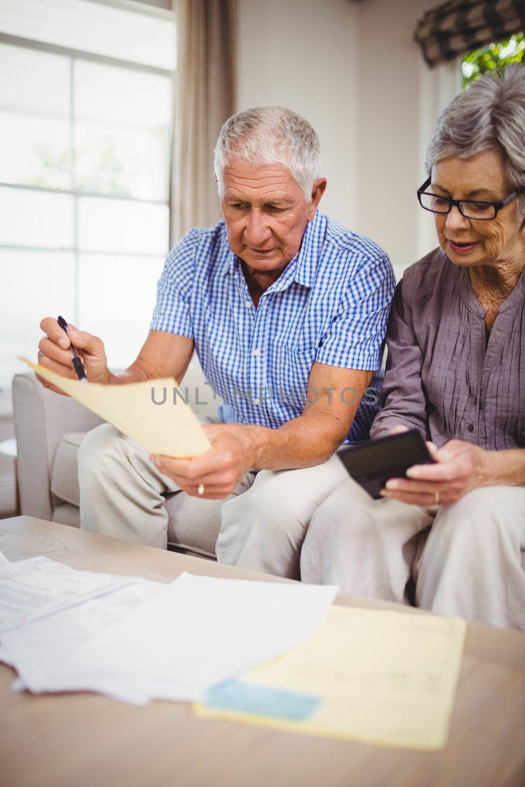 Senior couple calculating bills in living room by Wavebreakmedia