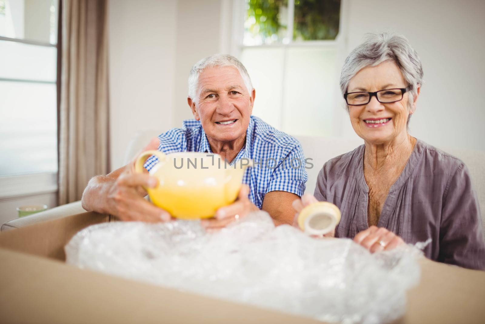 Portrait of senior couple unpacking a cardboard box in living room
