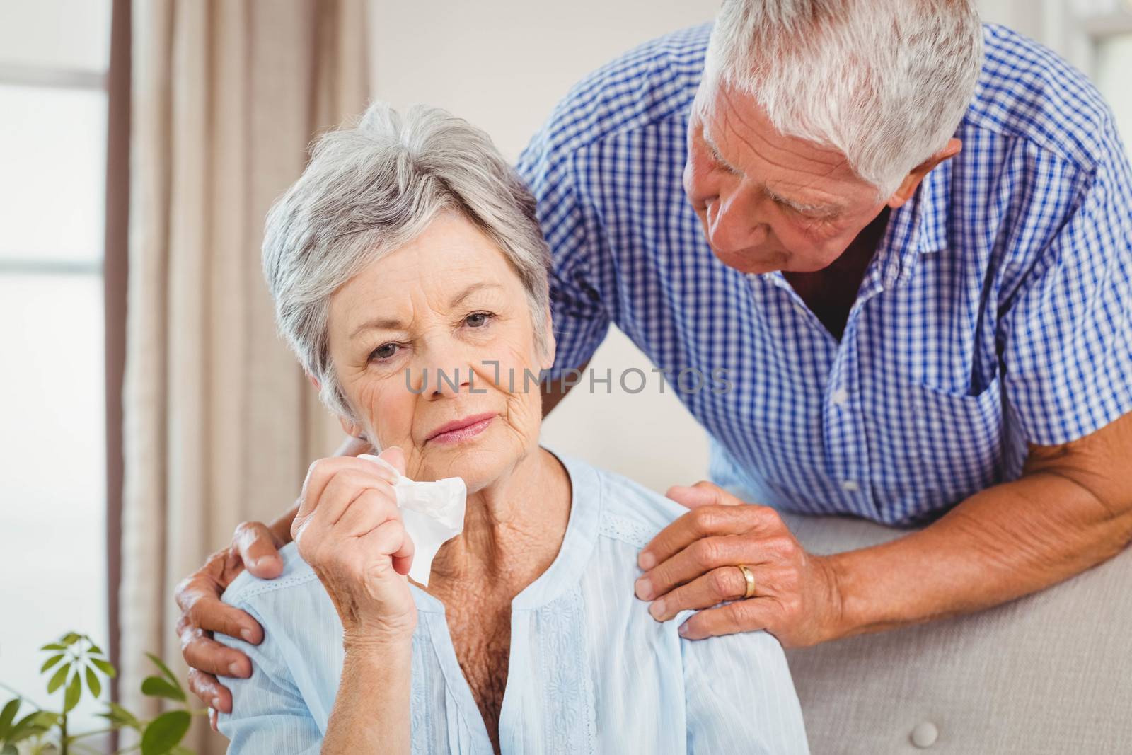 Senior man talking to upset senior woman in living room