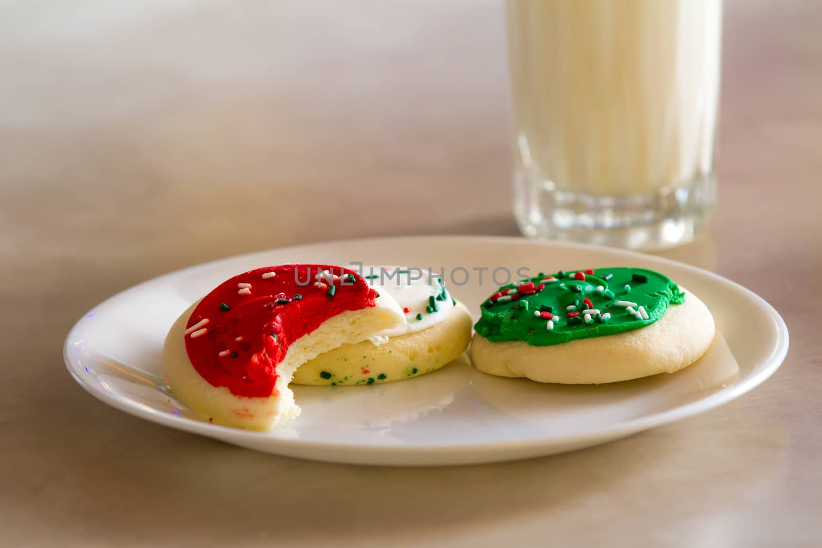 Cookies in front of some milk with a bite taken out of one of them