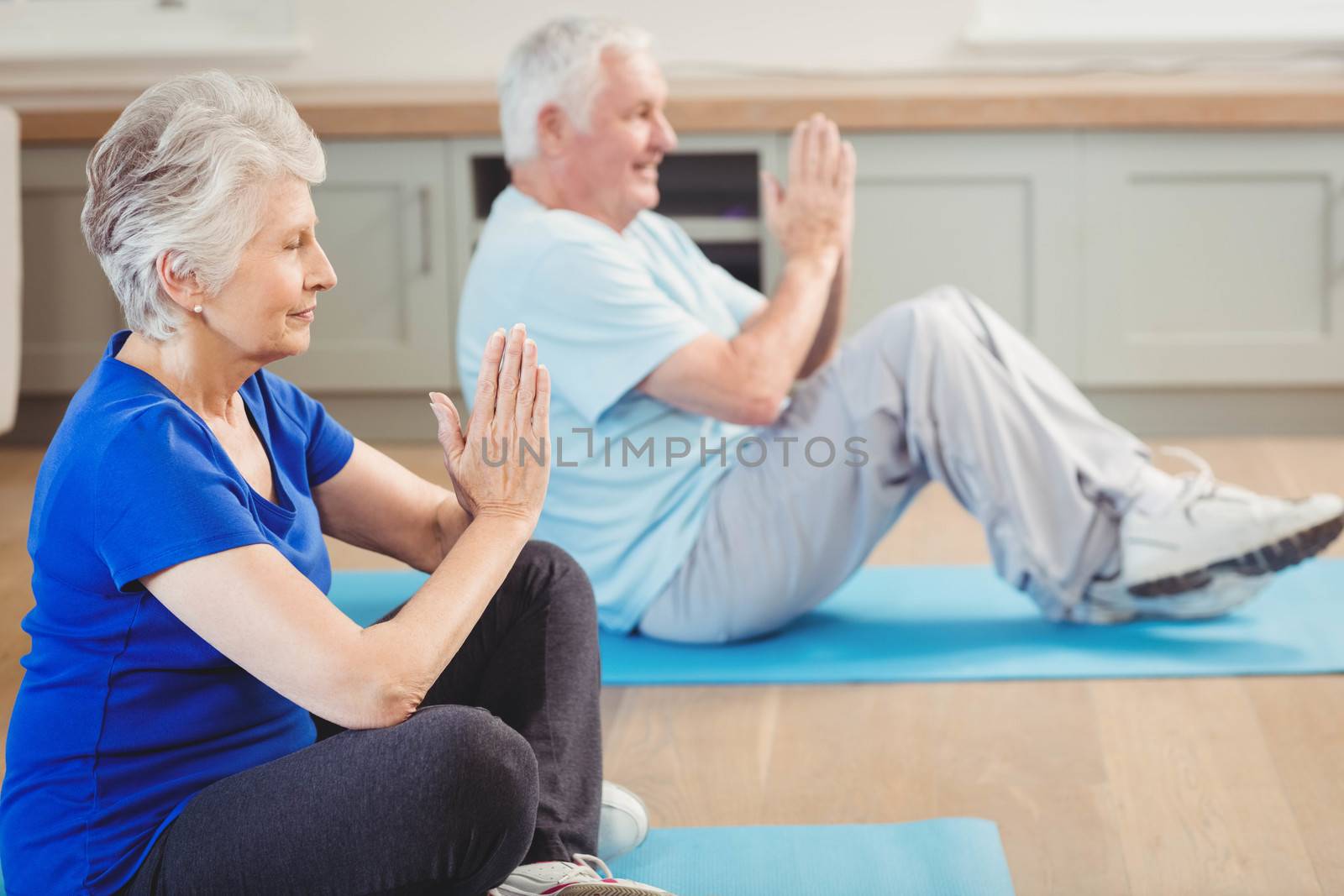 Senior couple performing yoga exercise by Wavebreakmedia