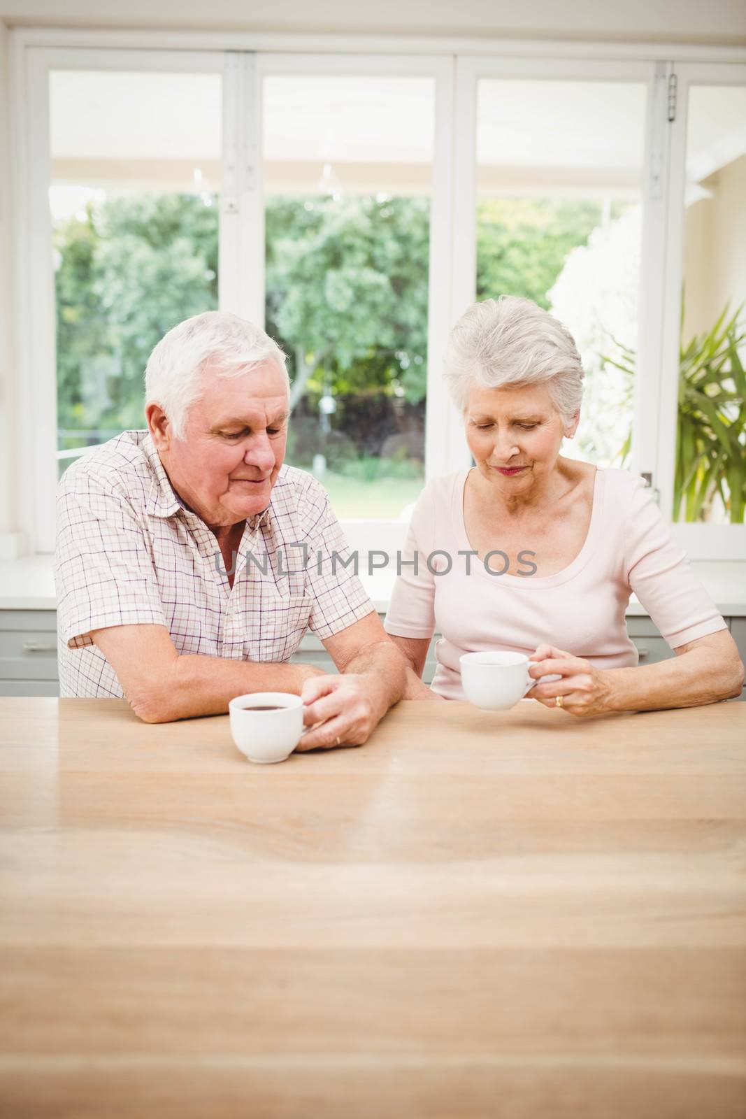 Senior couple talking to each other while having coffee by Wavebreakmedia