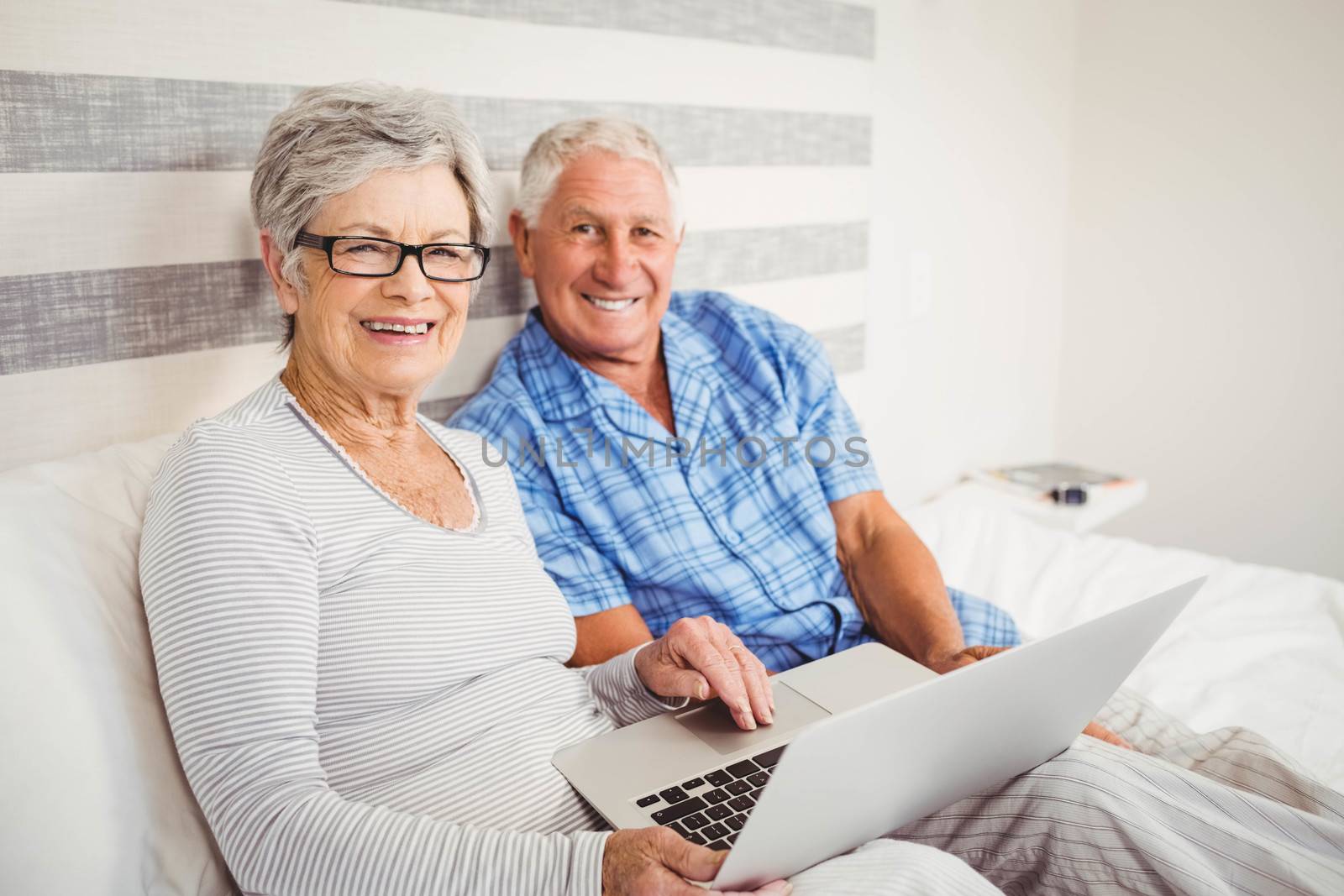Portrait of senior couple using laptop in bedroom