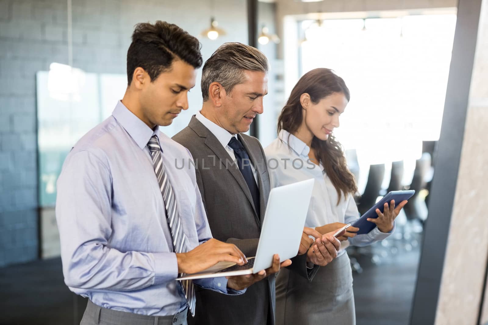 Businesspeople using mobile phone, lap top and digital tablet by Wavebreakmedia