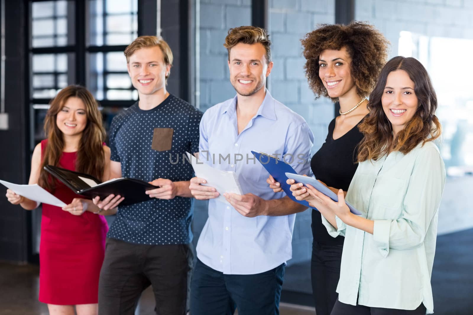 Portrait of colleagues standing in office with document and digital tablet