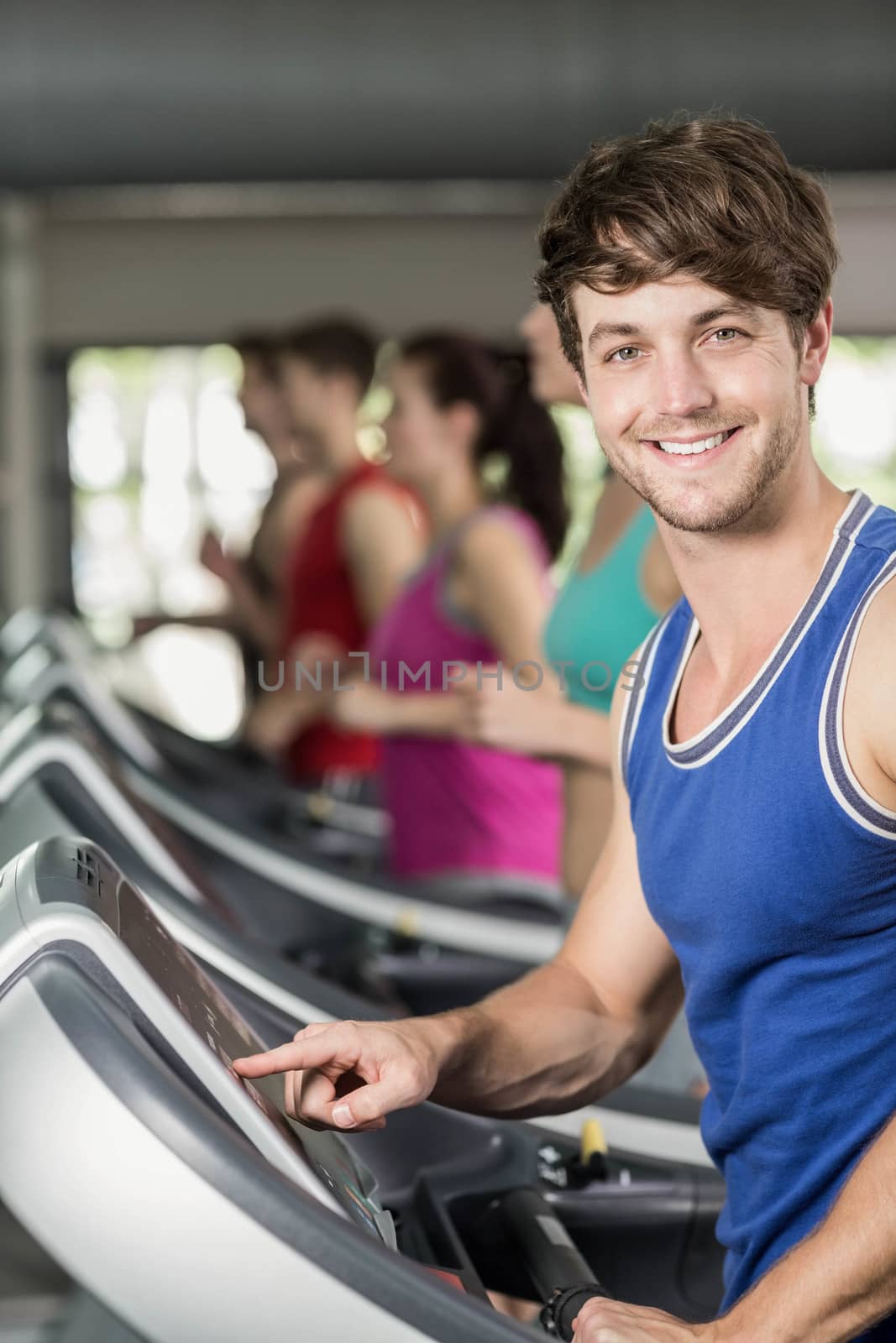 Smiling muscular man on treadmill  by Wavebreakmedia