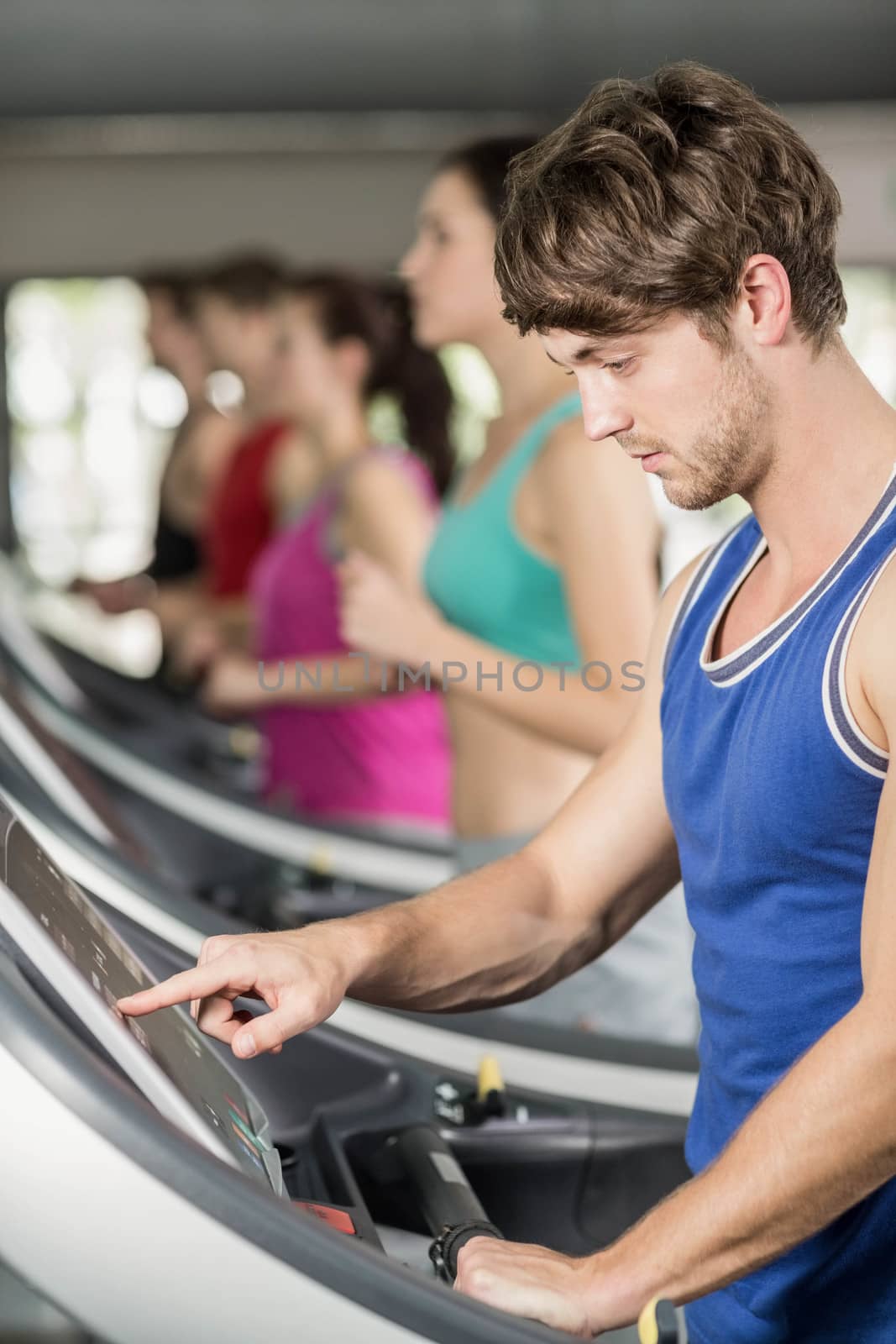 Smiling muscular man on treadmill at gym 