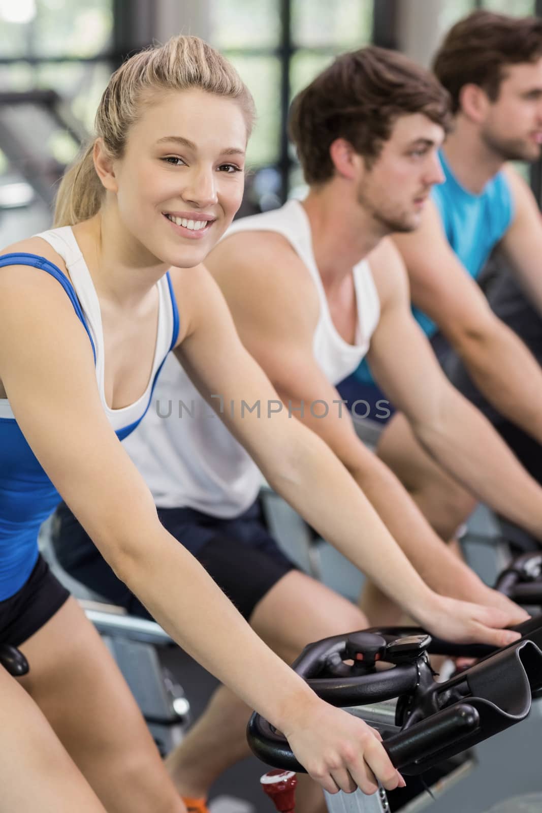 Fit group of people using exercise bike together by Wavebreakmedia