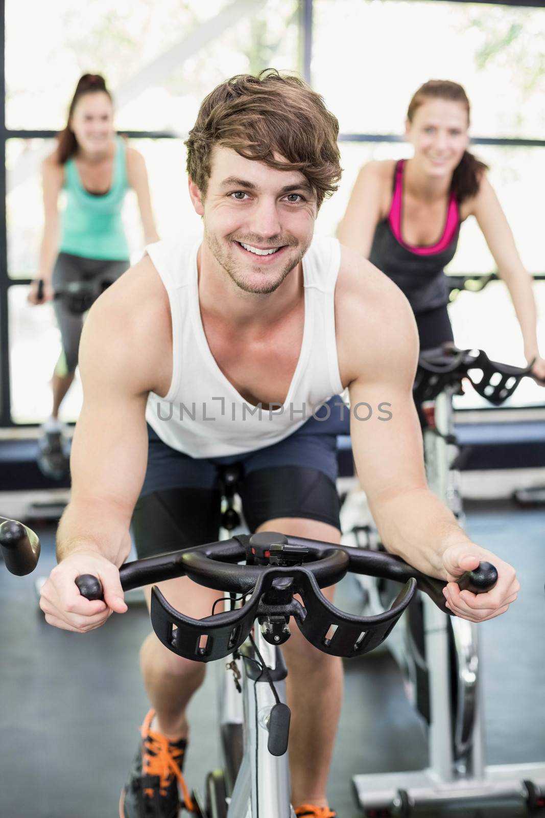 Fit group of people using exercise bike together by Wavebreakmedia